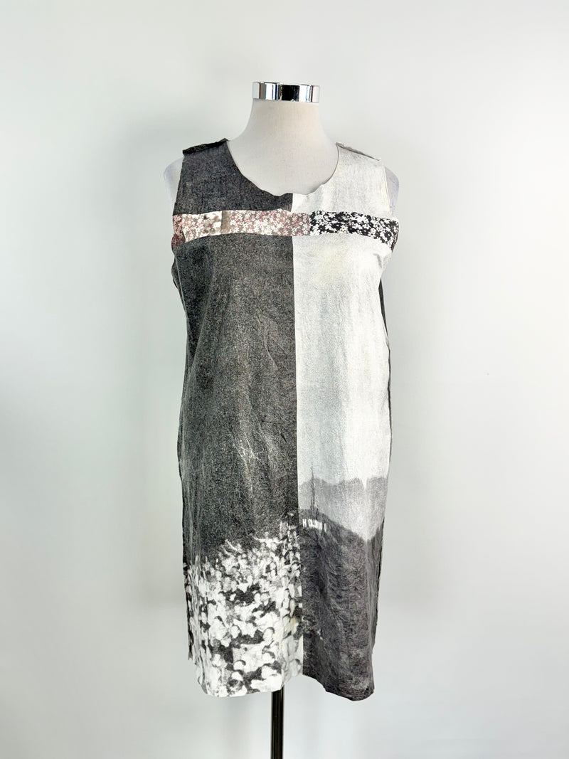 A sleeveless, knee-length tunic dress with a paperbag texture featuring a graphic print, displayed on a mannequin.