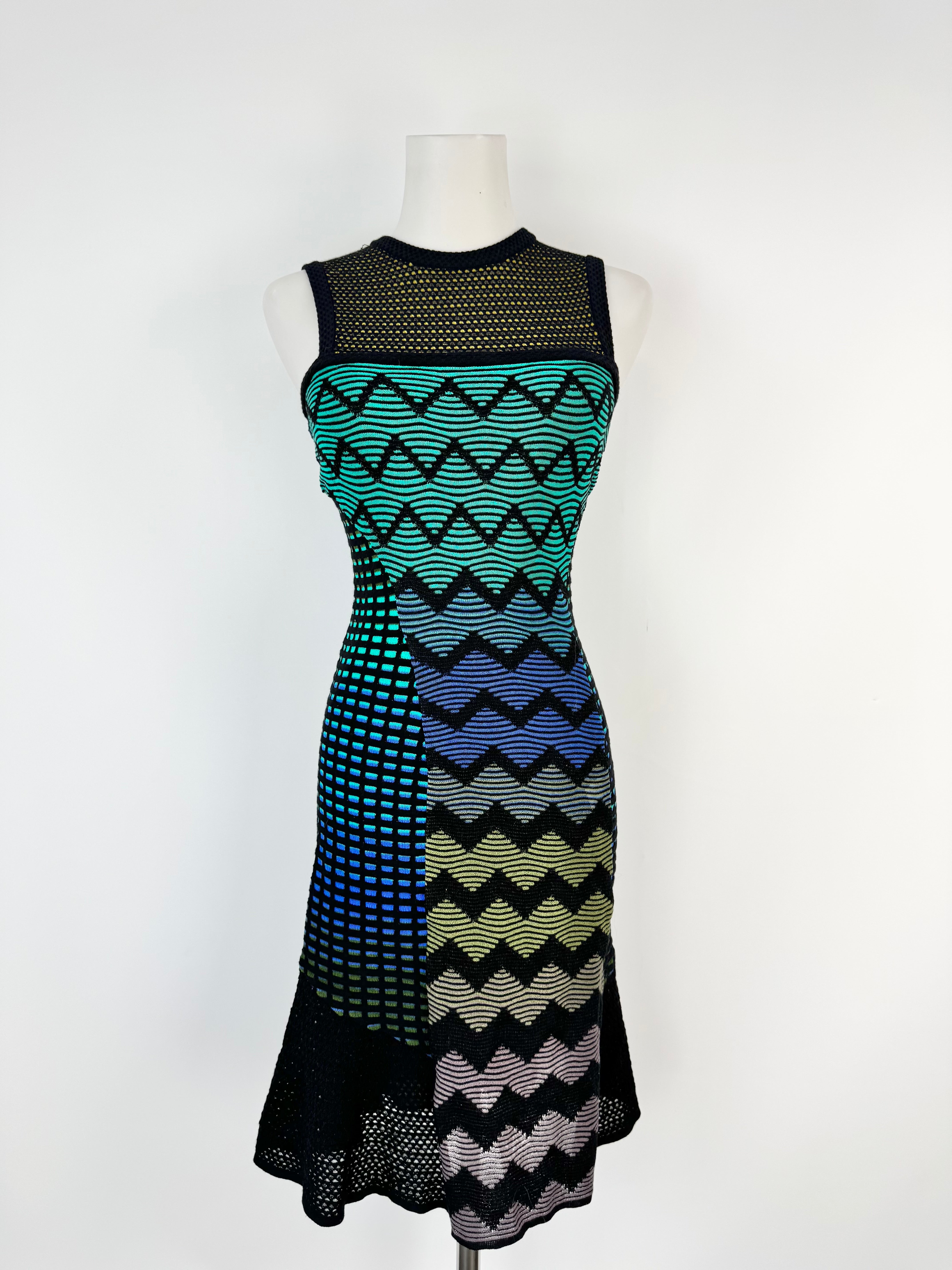 Mannequin wearing a black, blue, and green patterned dress on a white background