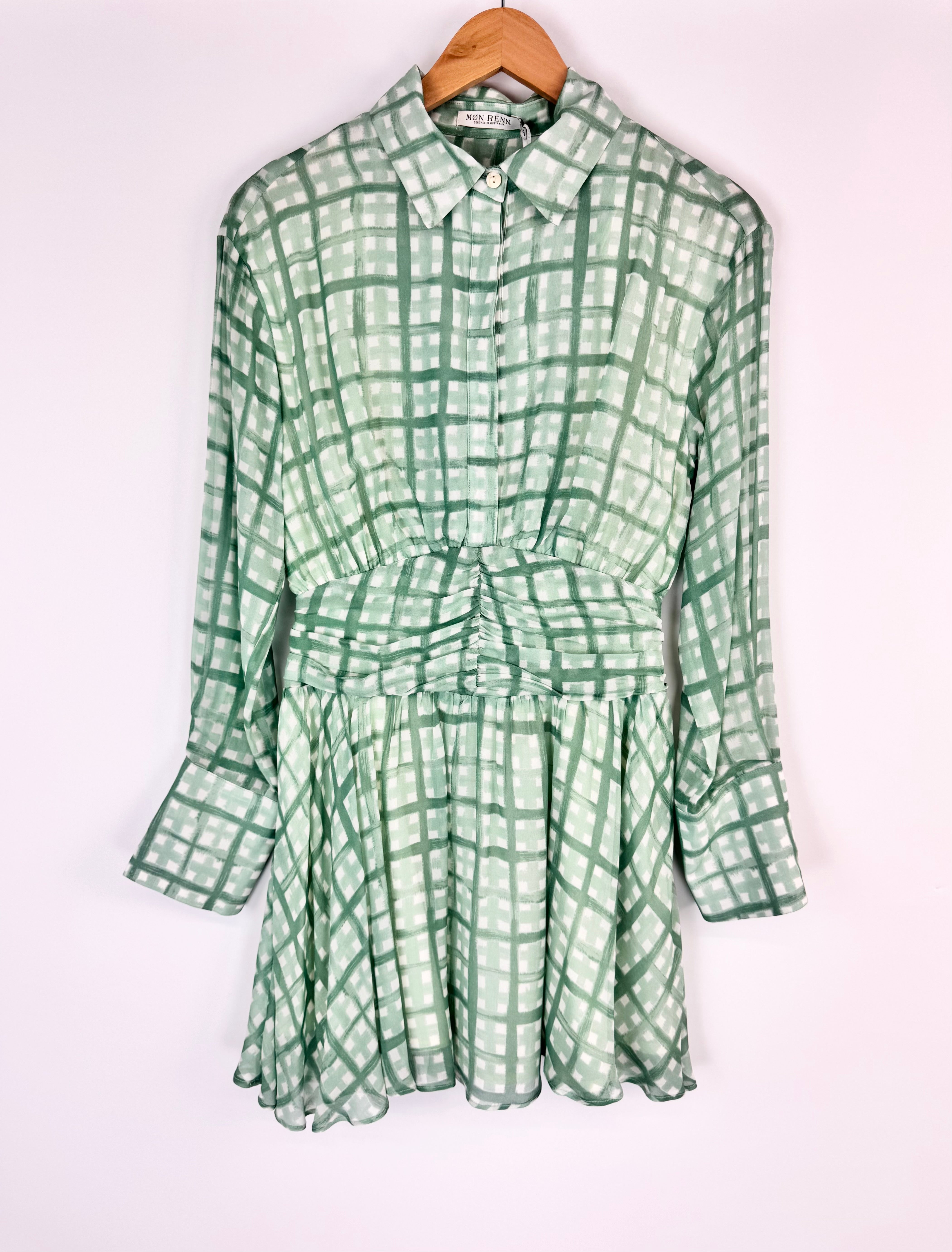 Green checkered dress on a hanger against a white background