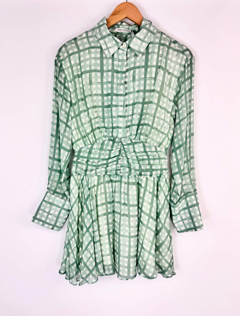 Green checkered dress on a hanger against a white background