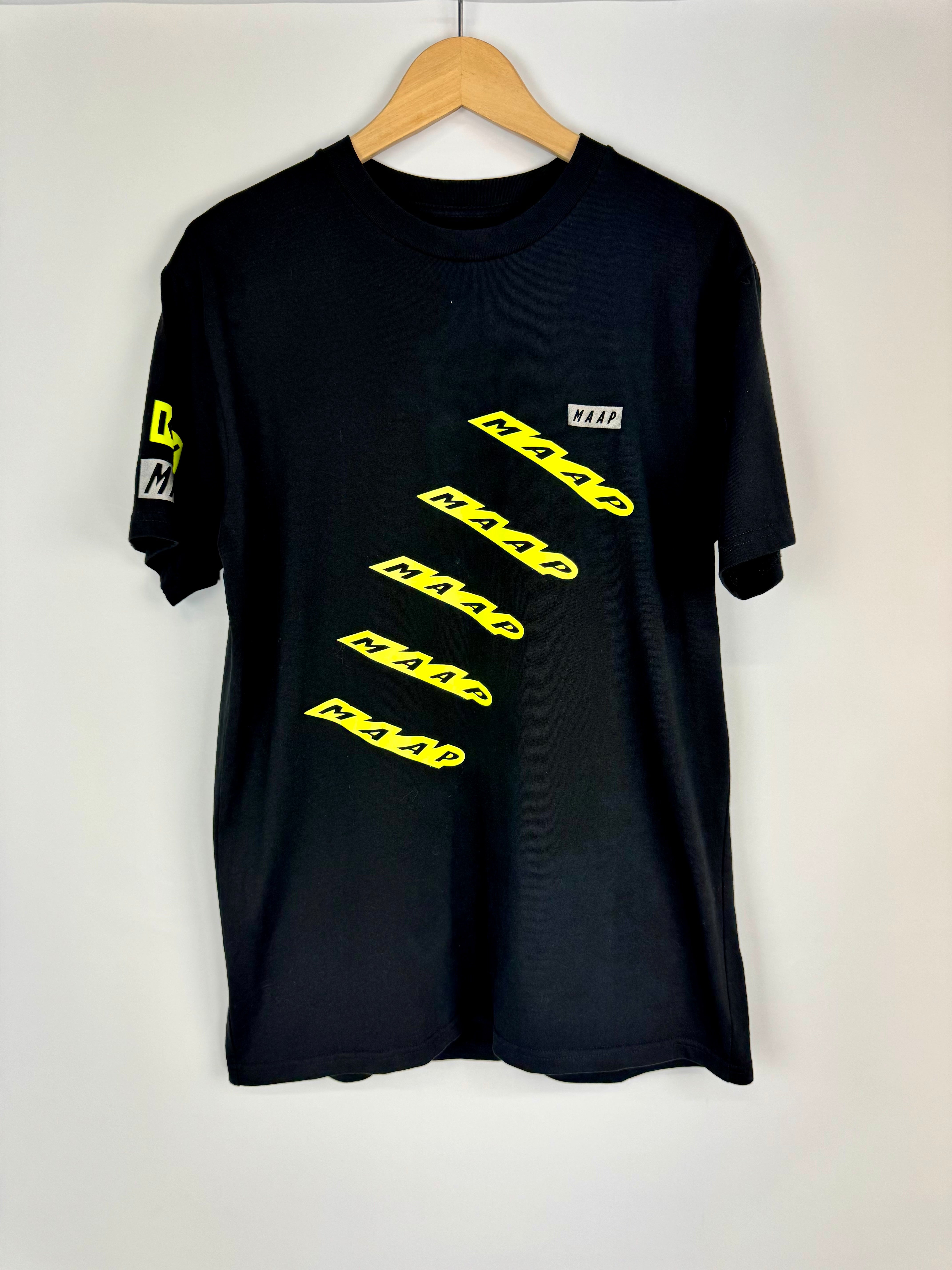 Black t-shirt with yellow text on a hanger against a white background