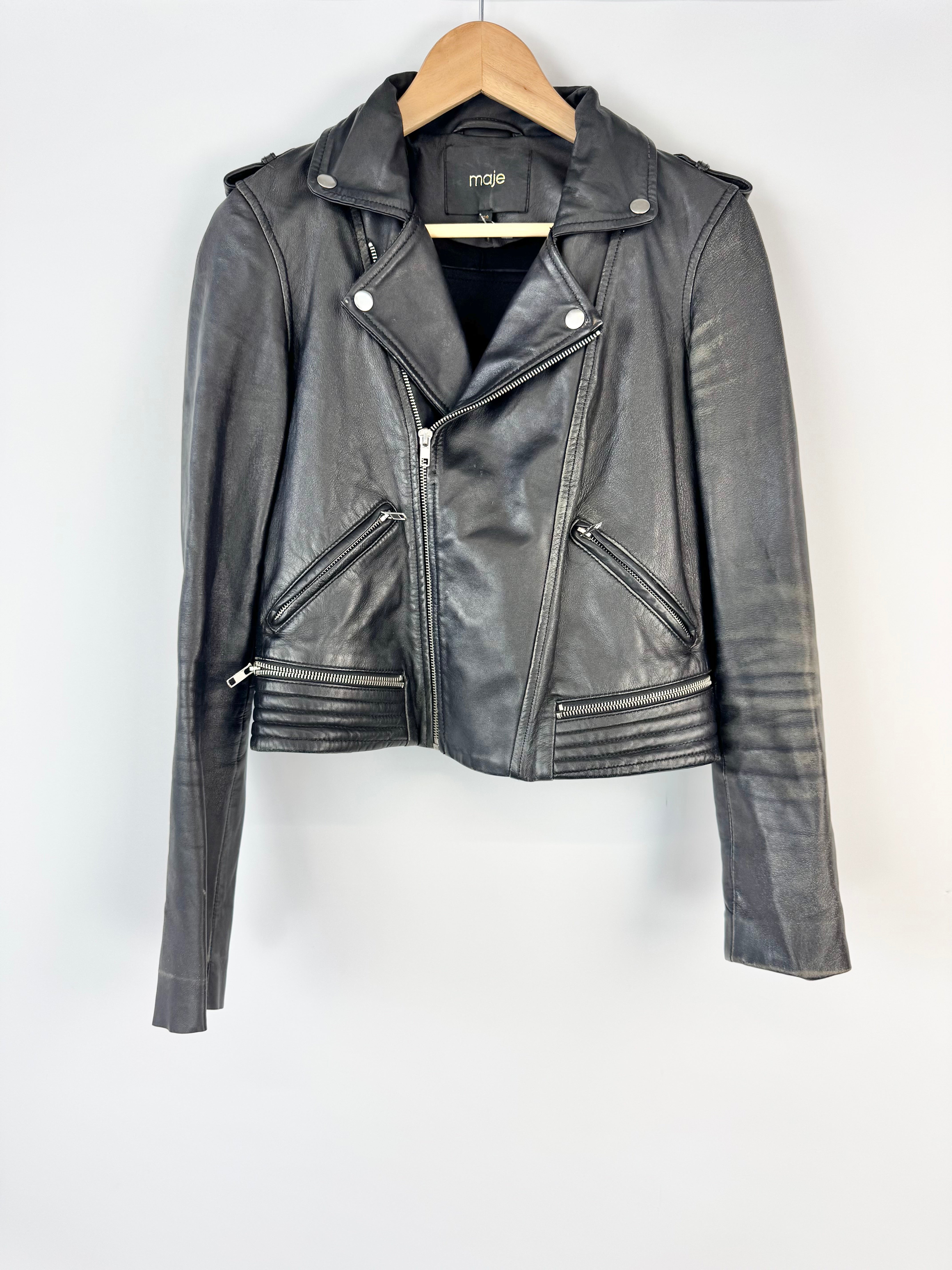 Black leather jacket on a hanger against a white background