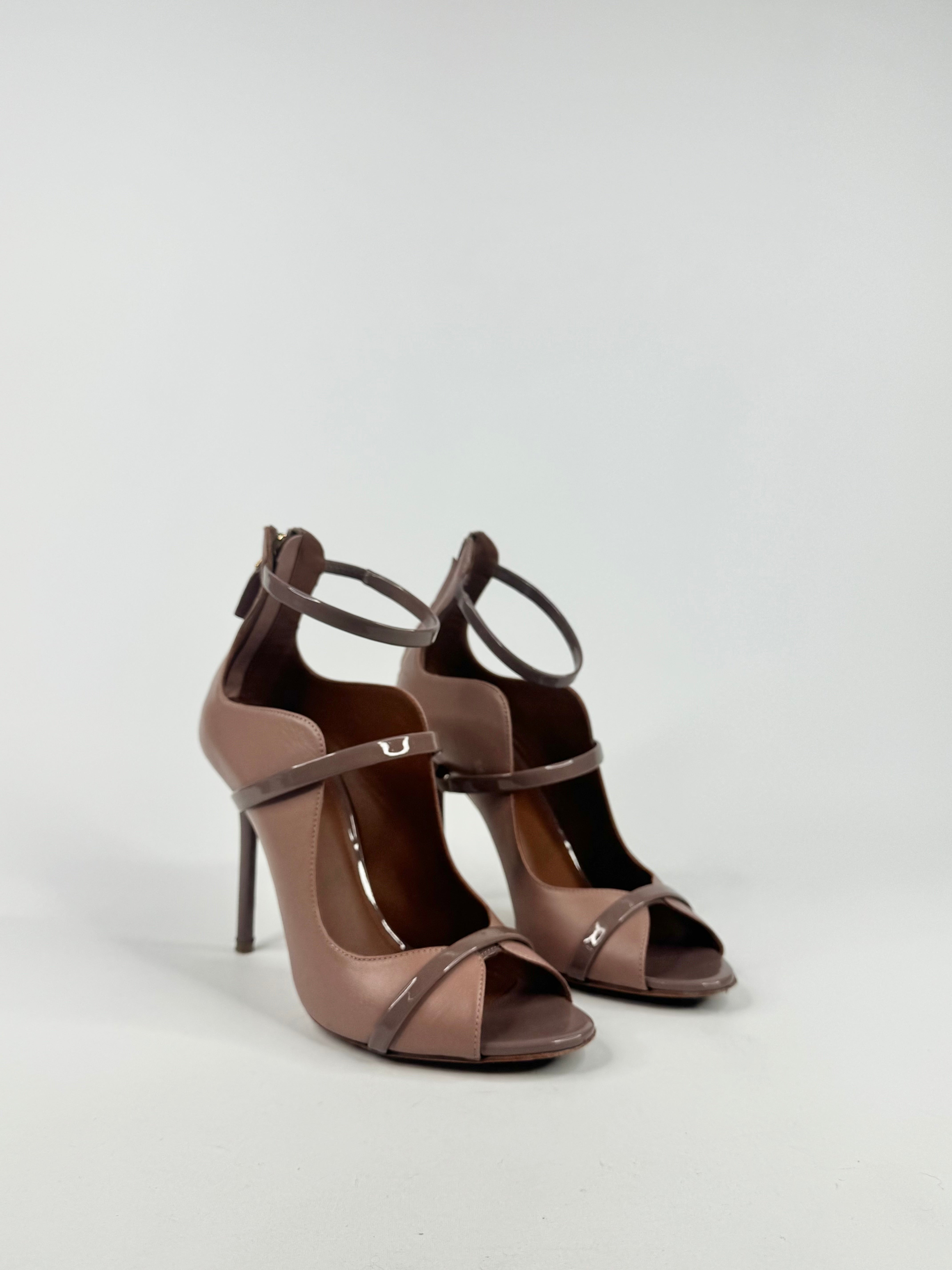 Pair of brown high-heeled sandals on a light gray background