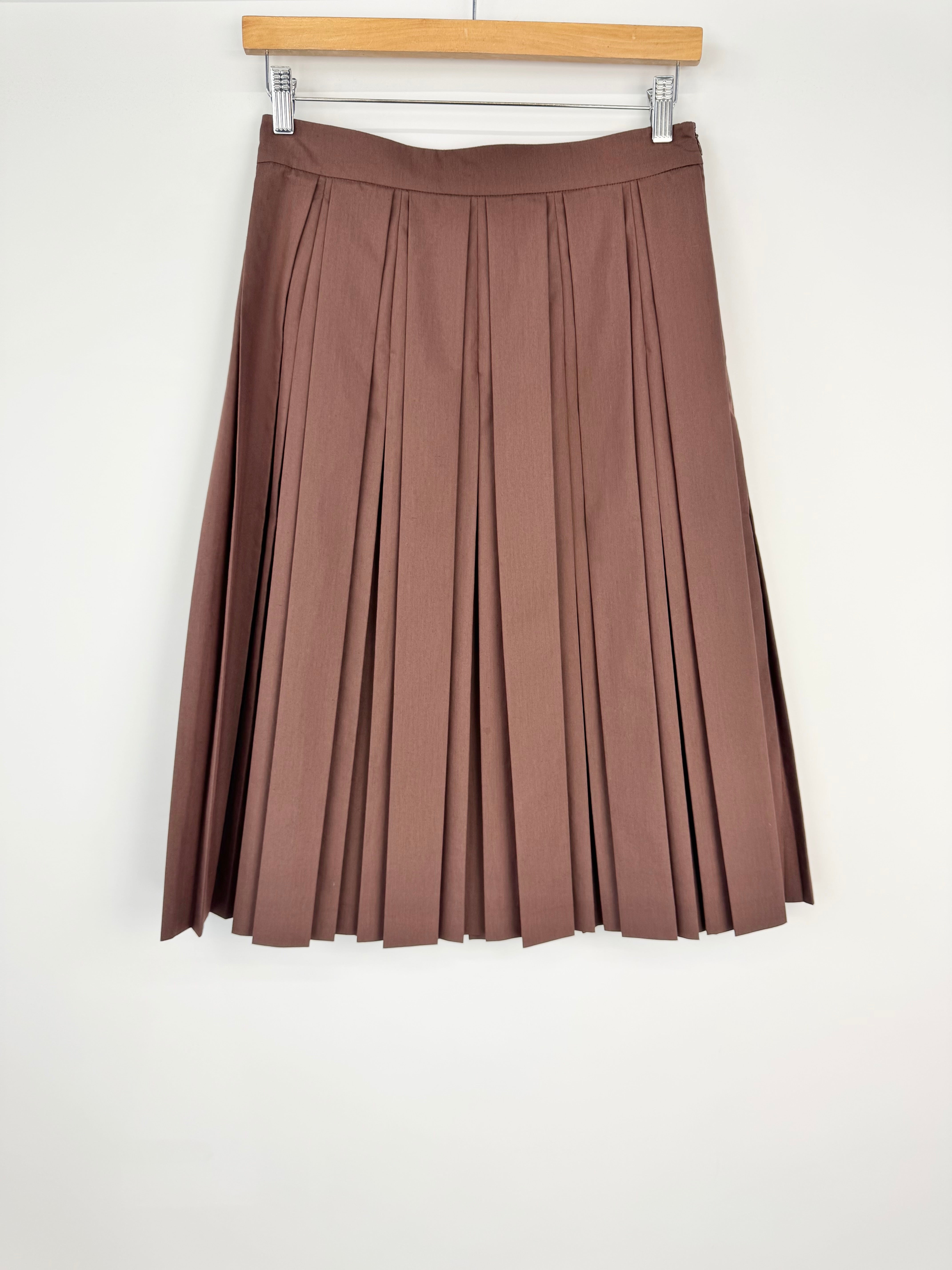 Brown pleated skirt on a hanger against a white background