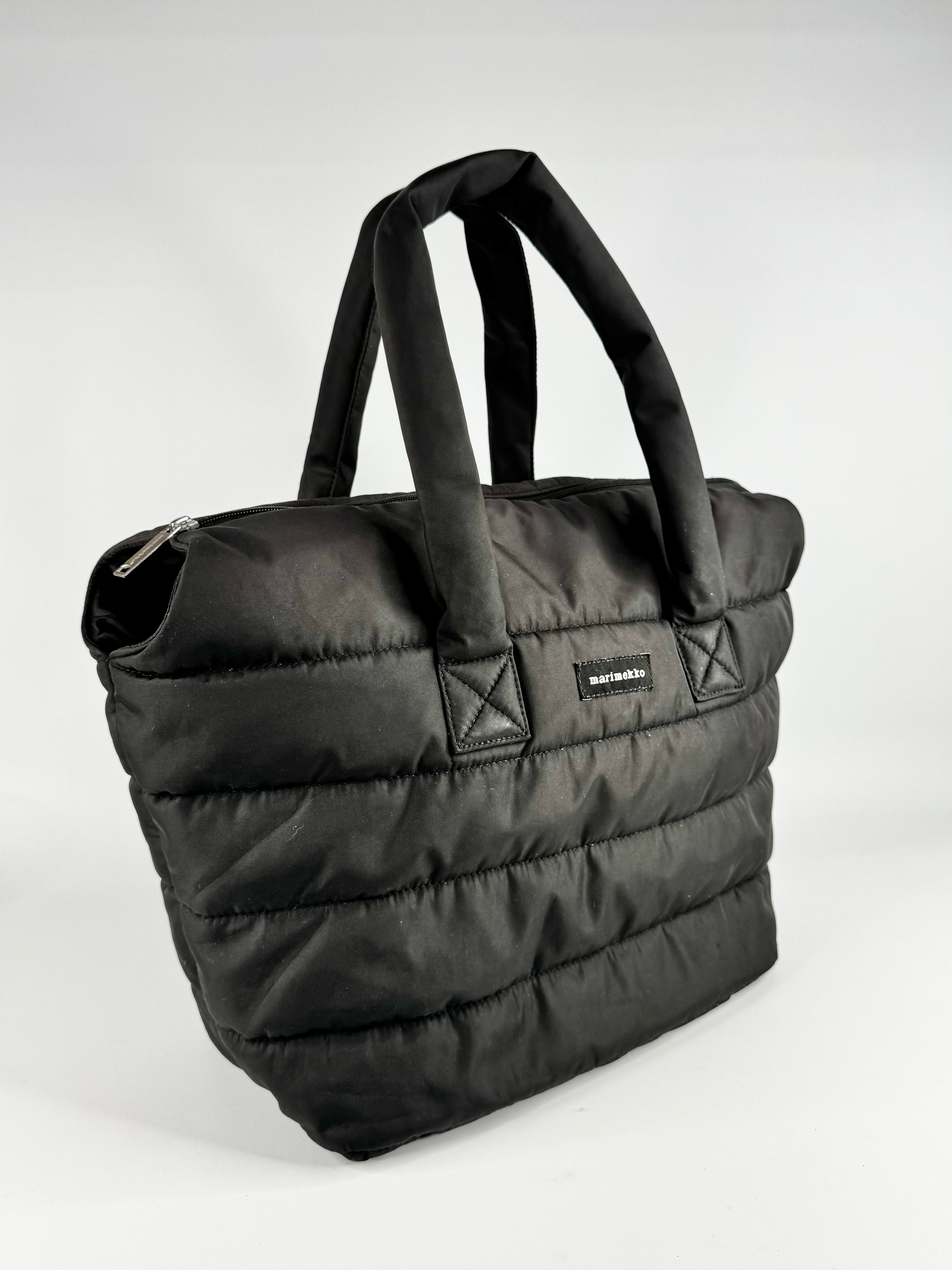Black quilted bag with a visible brand logo on a white background