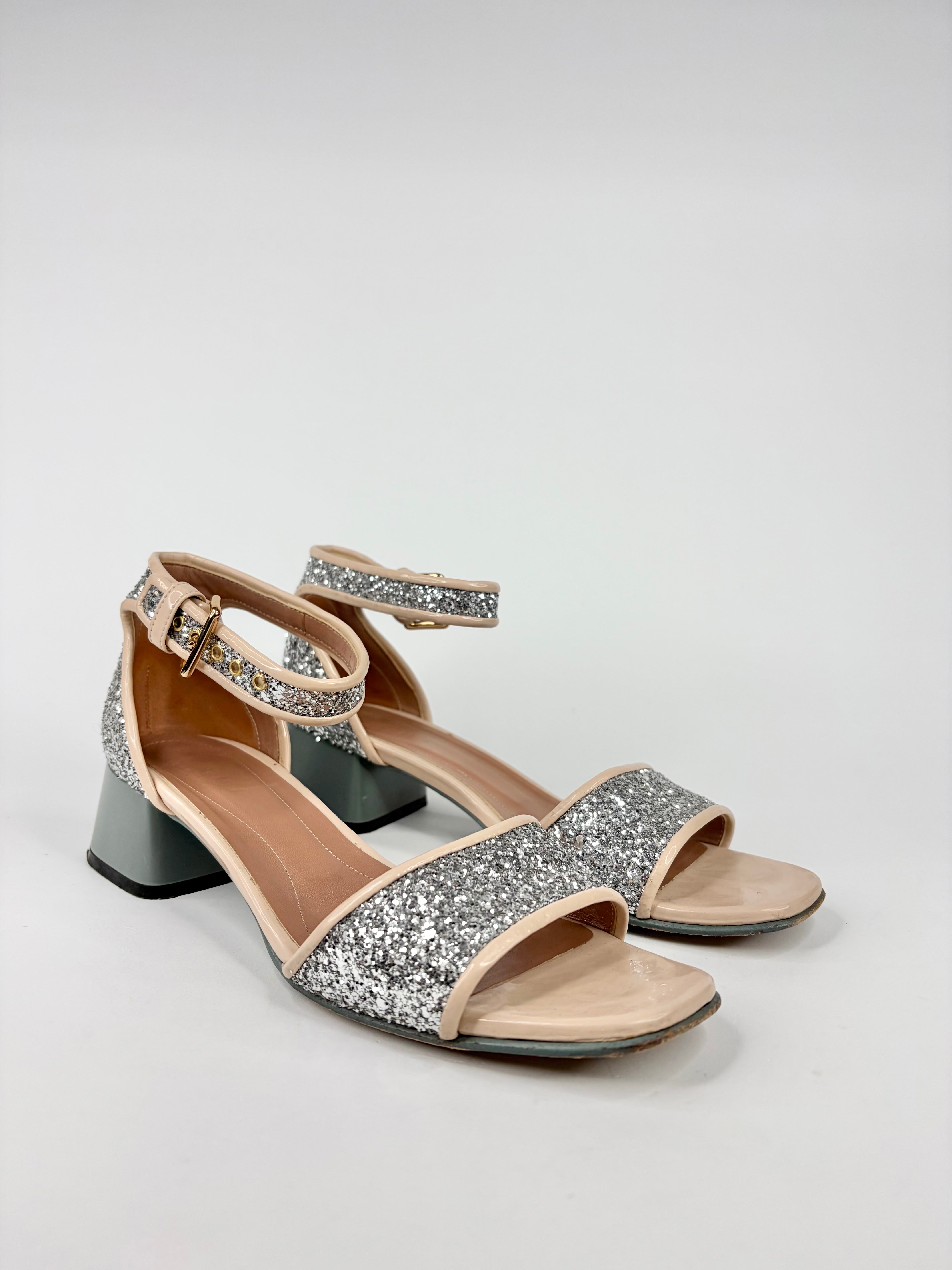 Pair of glittery high-heeled sandals on a light gray background