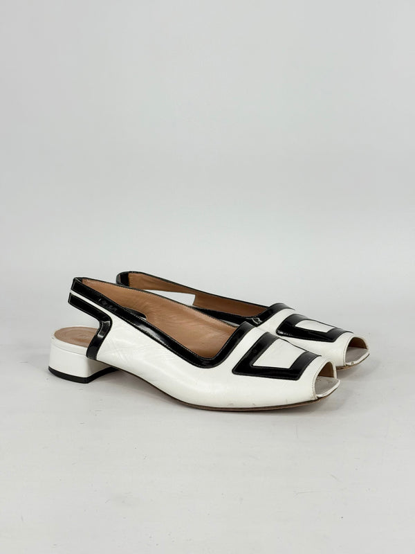 White and black open-toe shoes on a light gray background