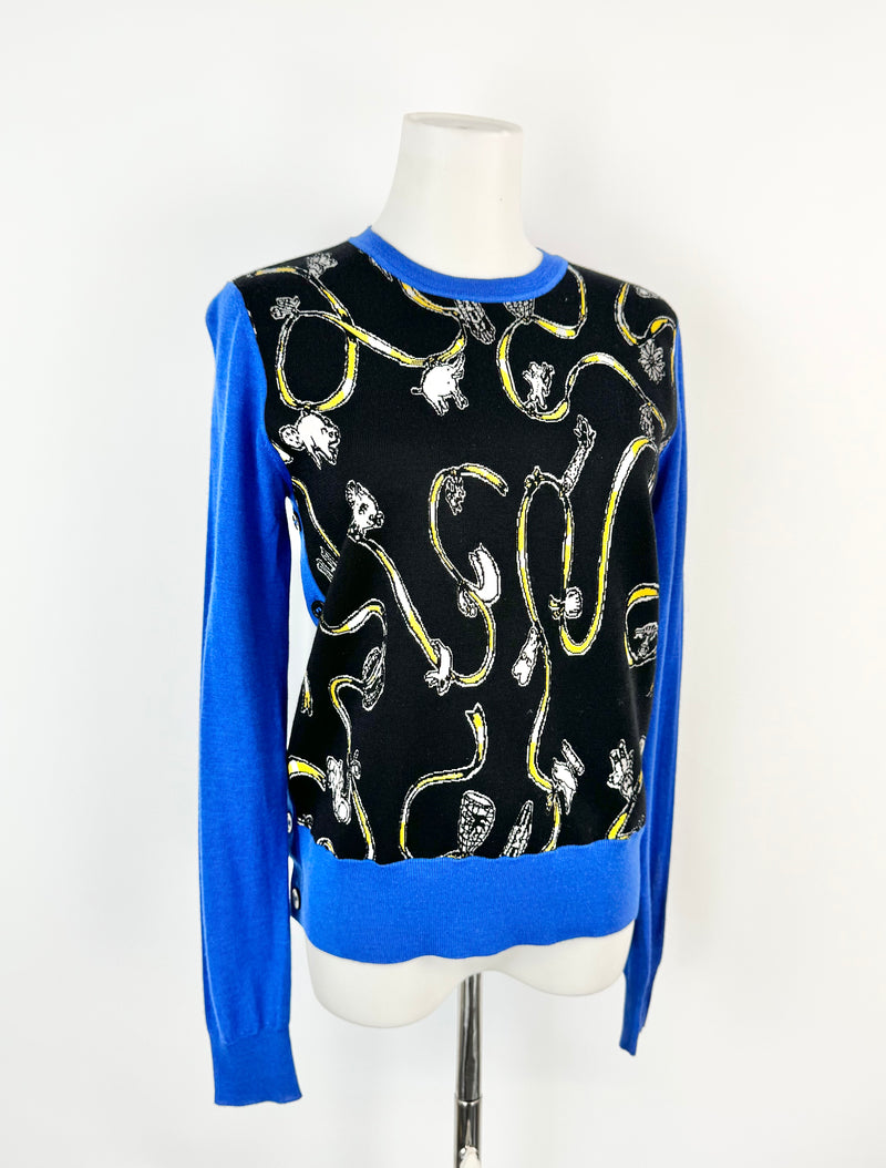 Mannequin wearing a black sweater with blue sleeves and gold patterns on a white background