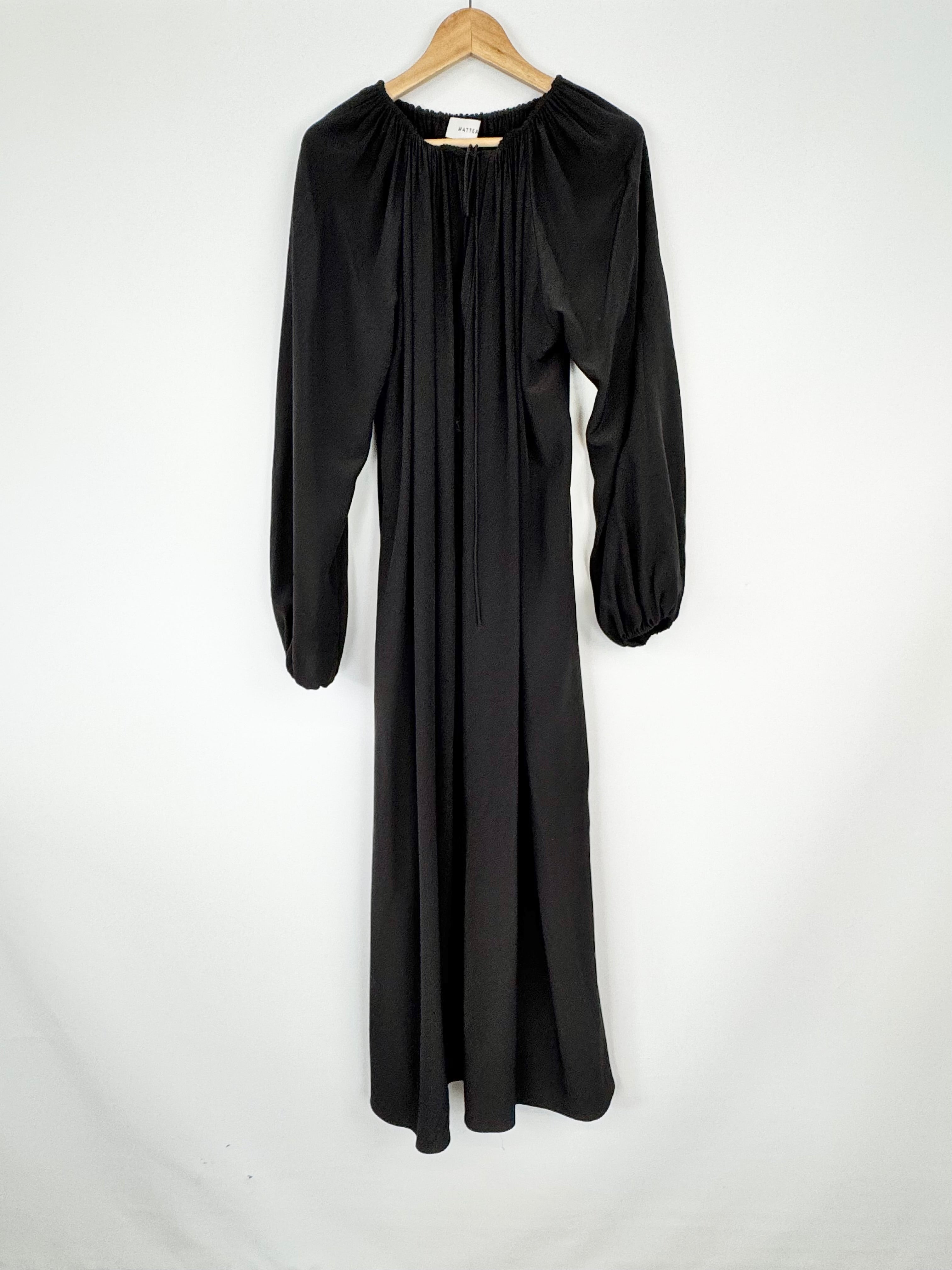 Black dress on a hanger against a white background