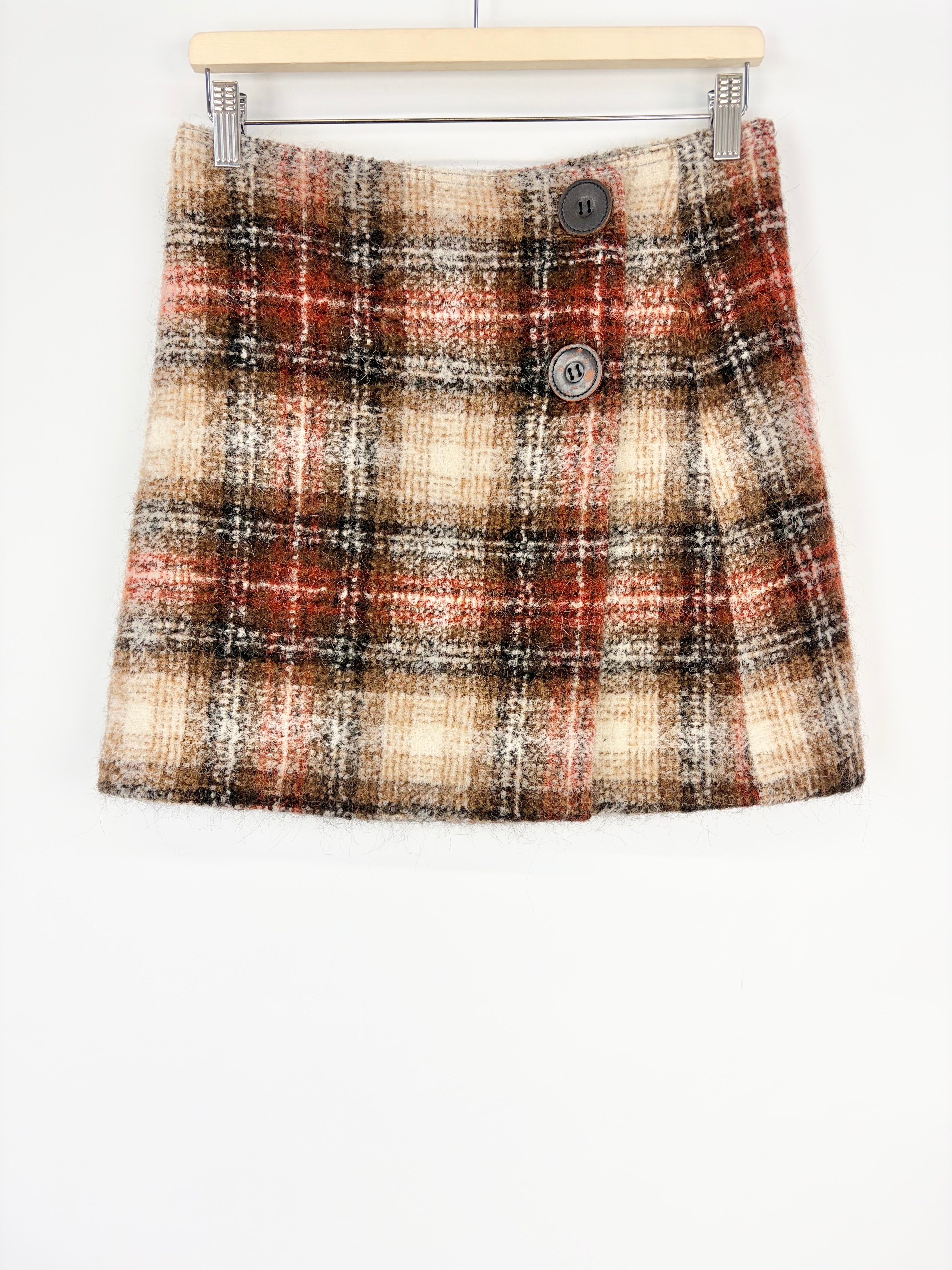 Plaid skirt on a hanger against a white background