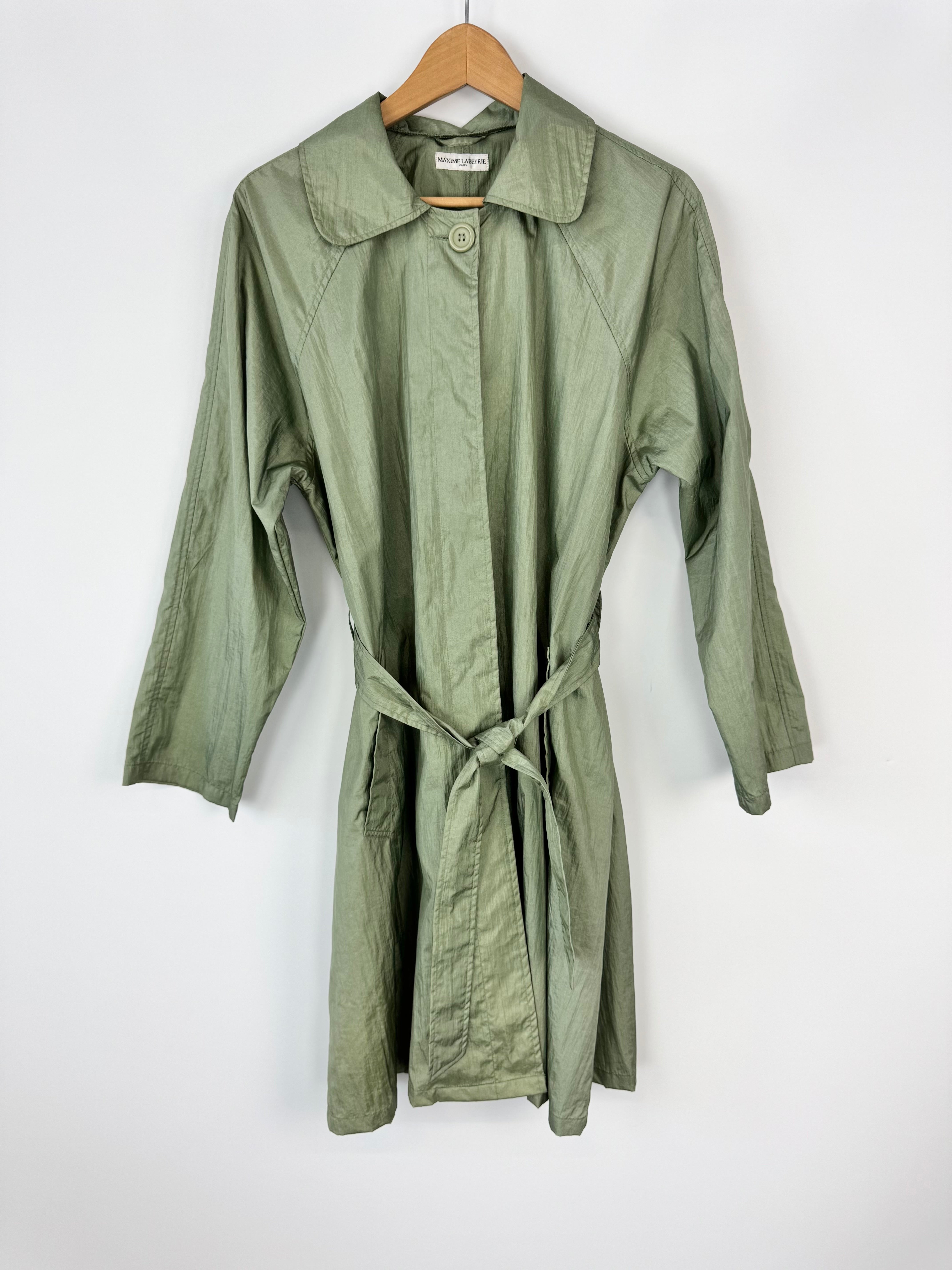 Green trench coat on a hanger against a white background