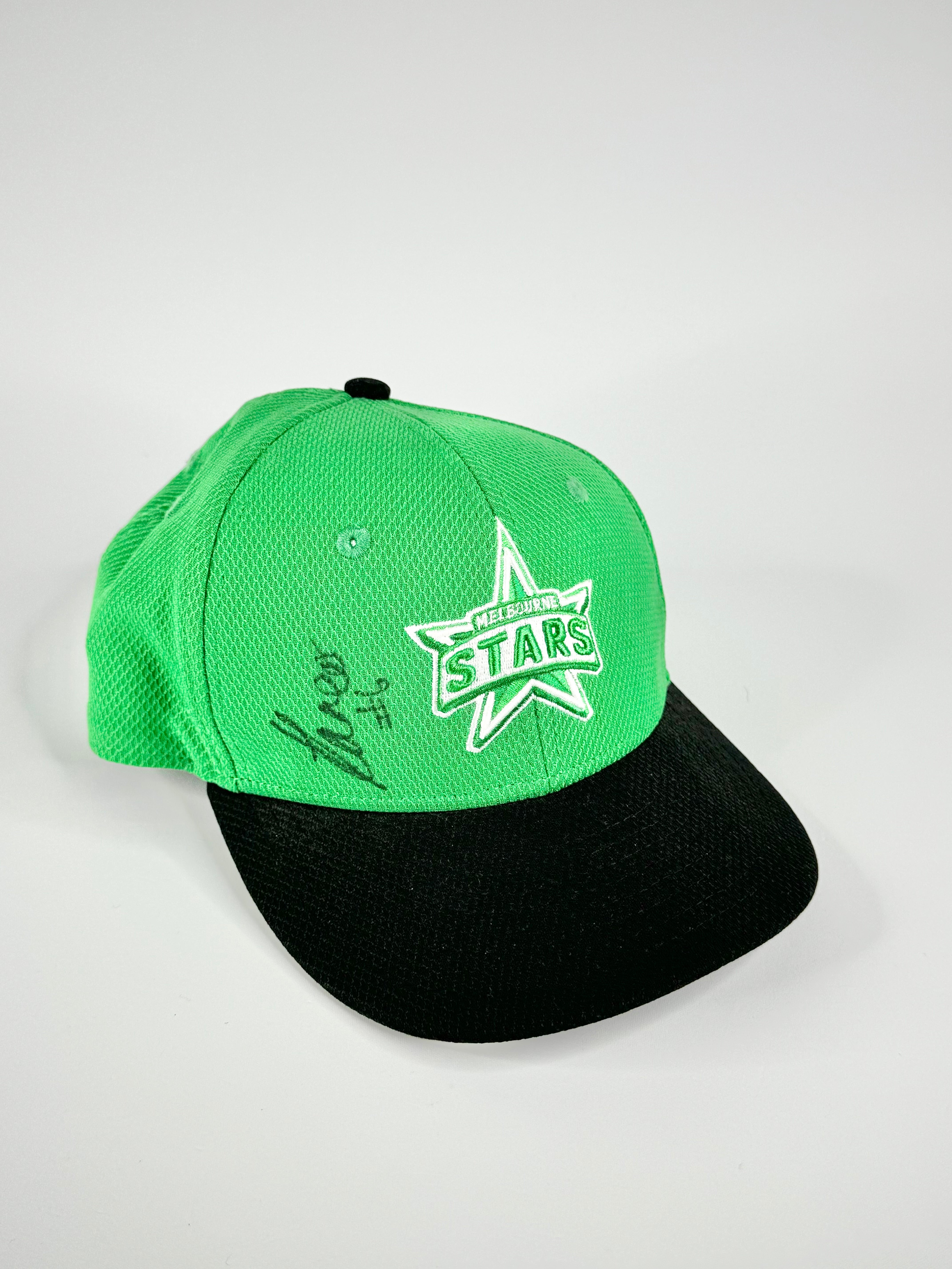 A green baseball cap with Melbourne Stars branding and a signature, although the signature is not recognizable.