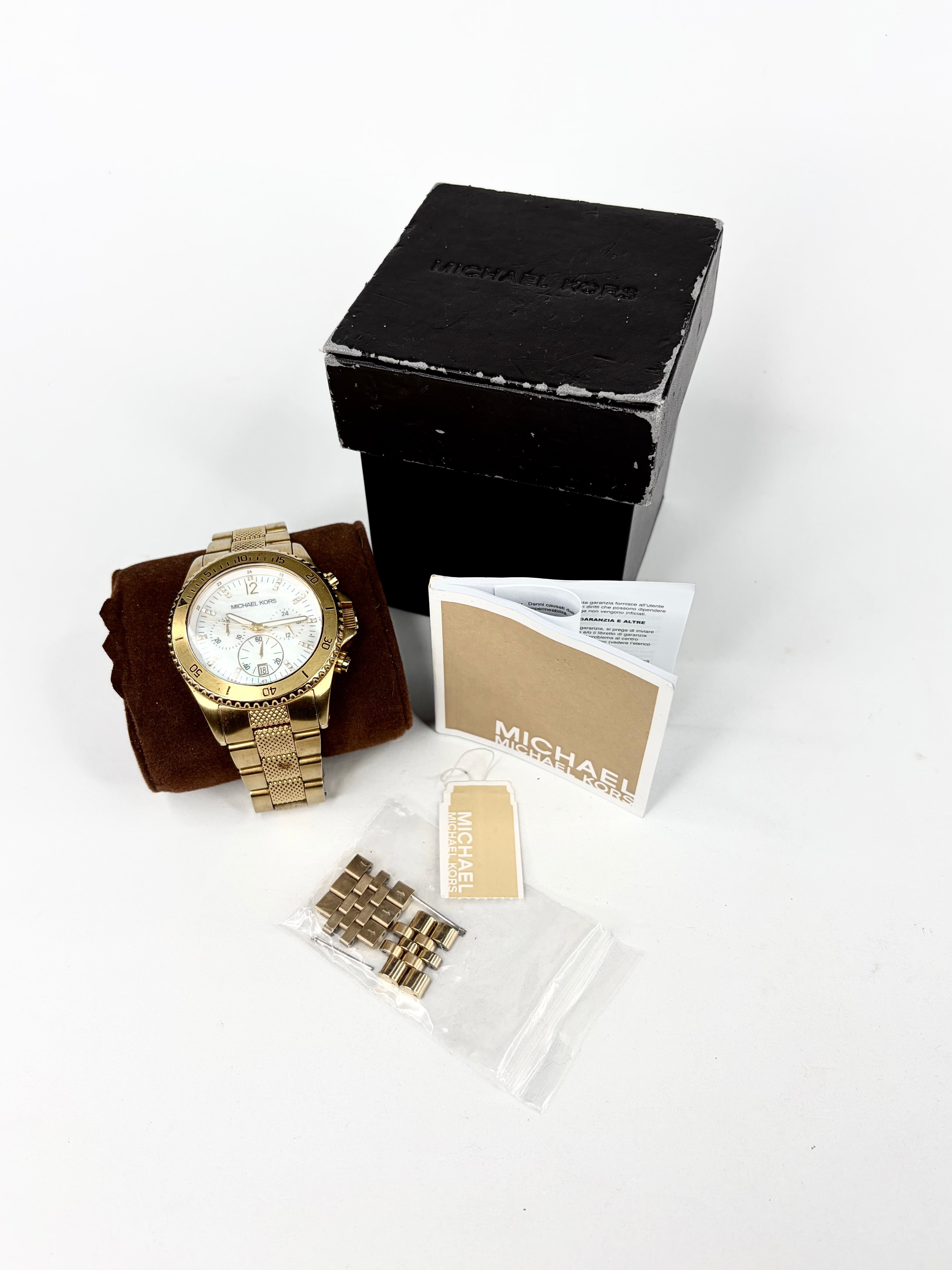 Gold watch with packaging and accessories on a white background
