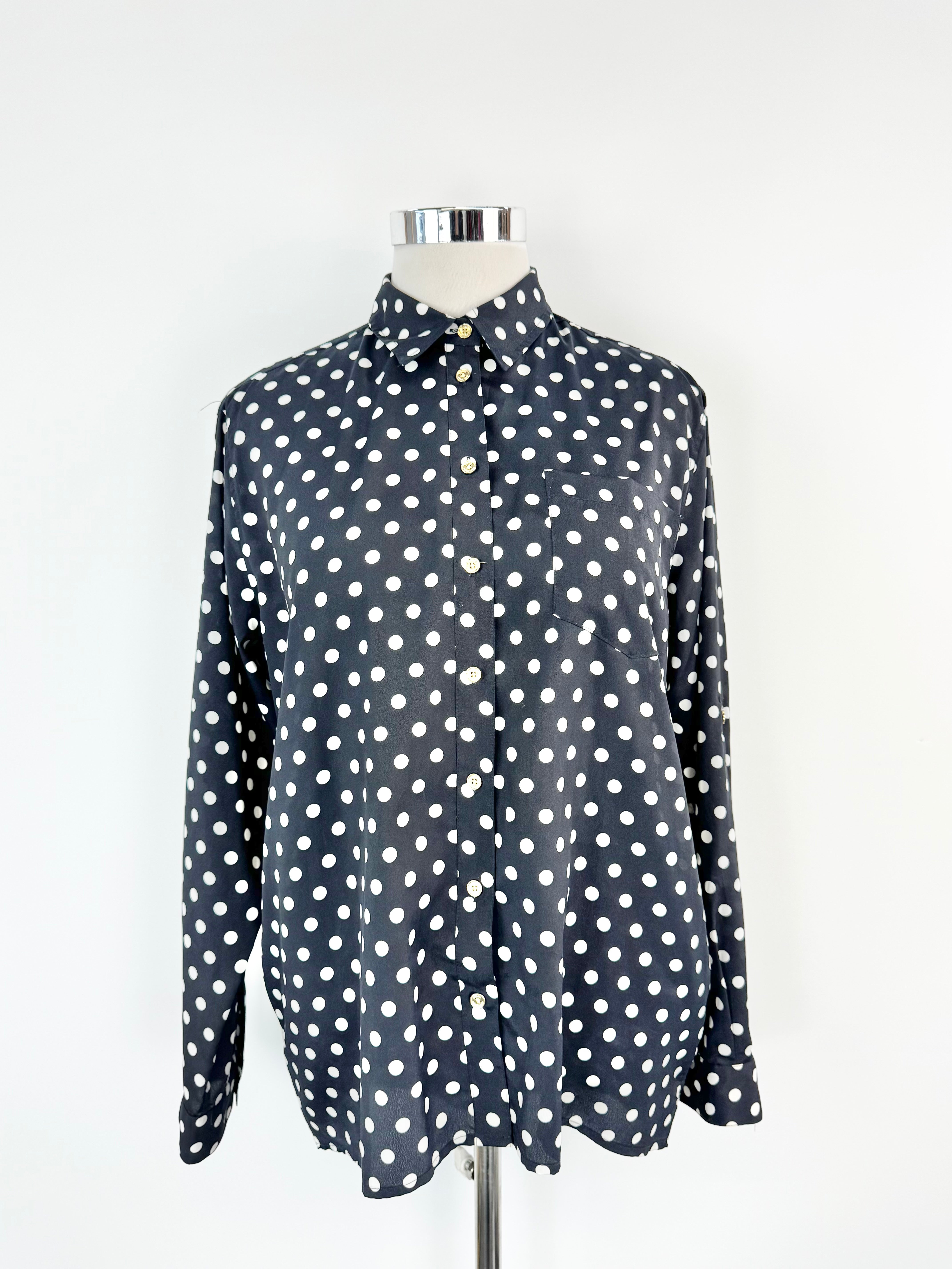 Black shirt with white polka dots on a mannequin against a white background