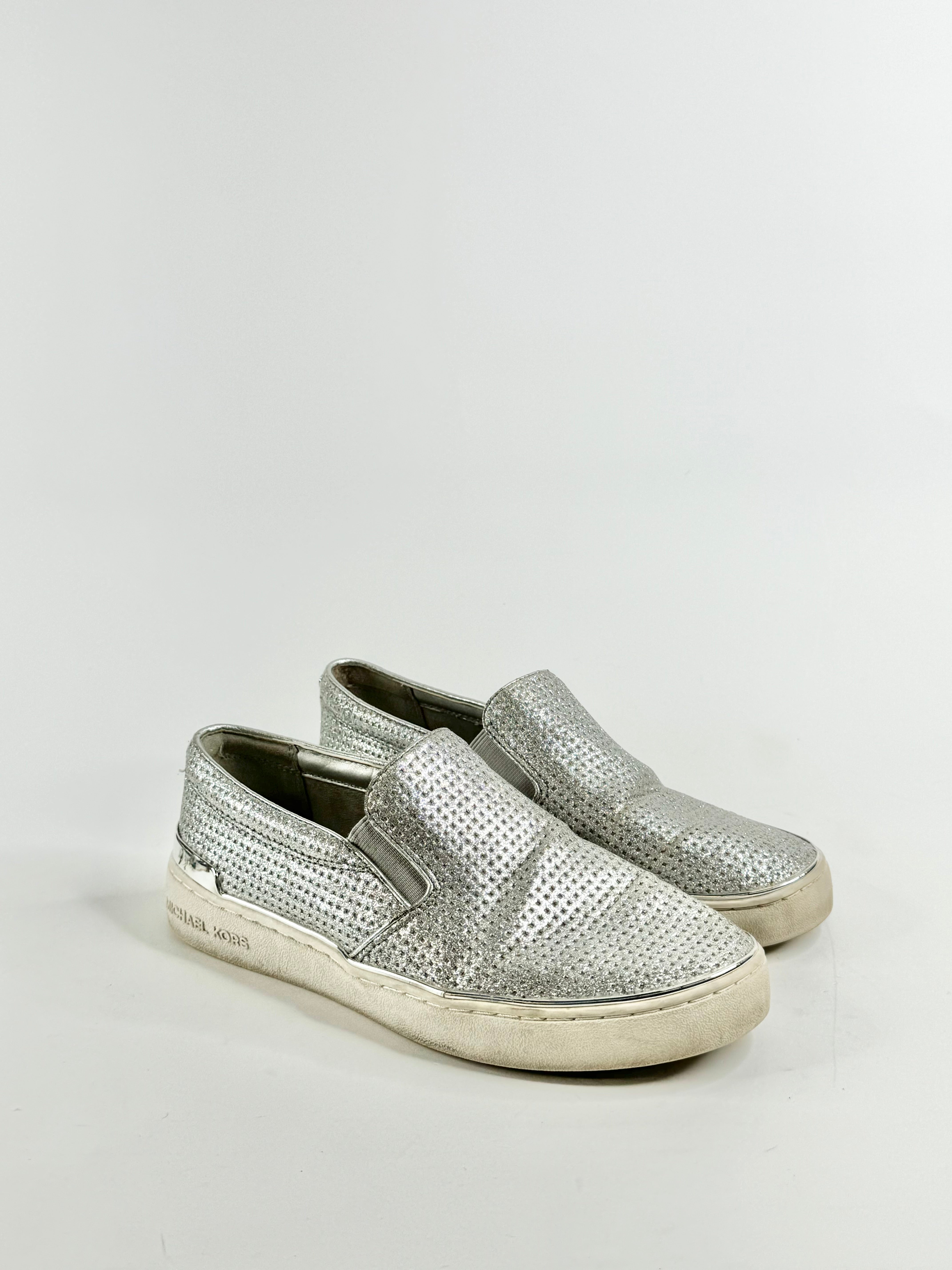 A pair of silver glittery slip-on shoes with a flat sole.