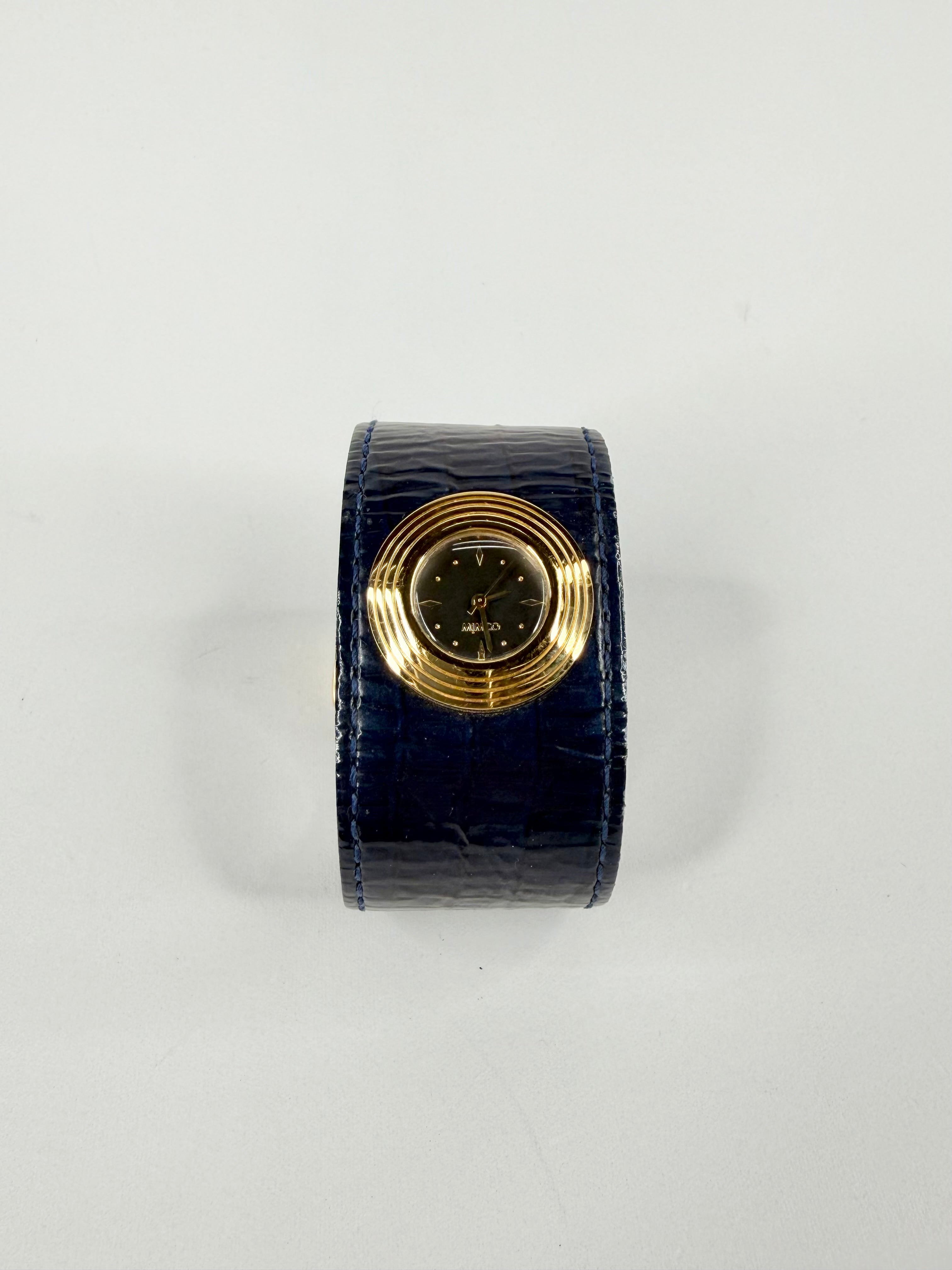 Black watch holder with gold watch on a white background