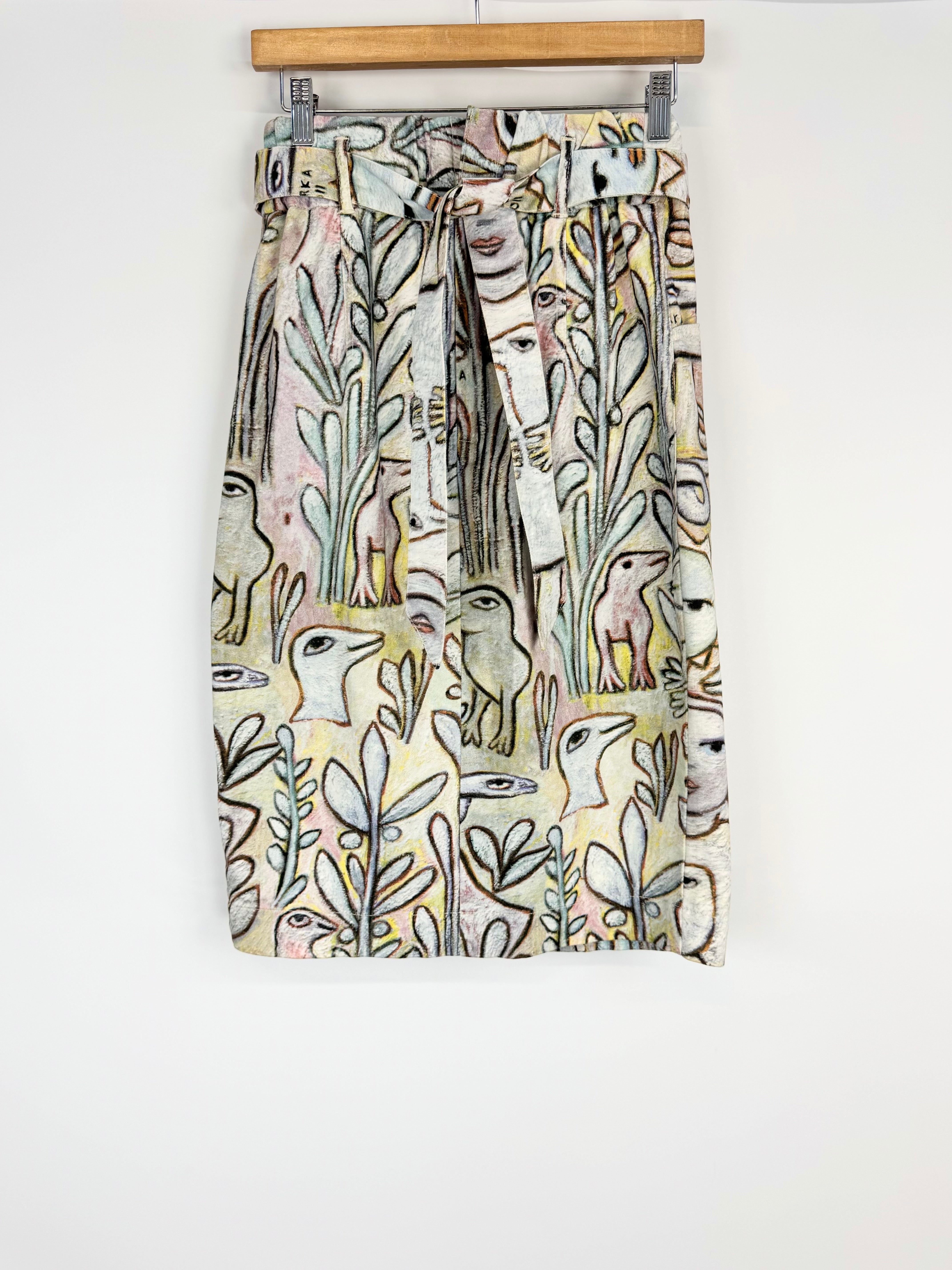Skirt with nature-themed design on a wooden hanger against a white background