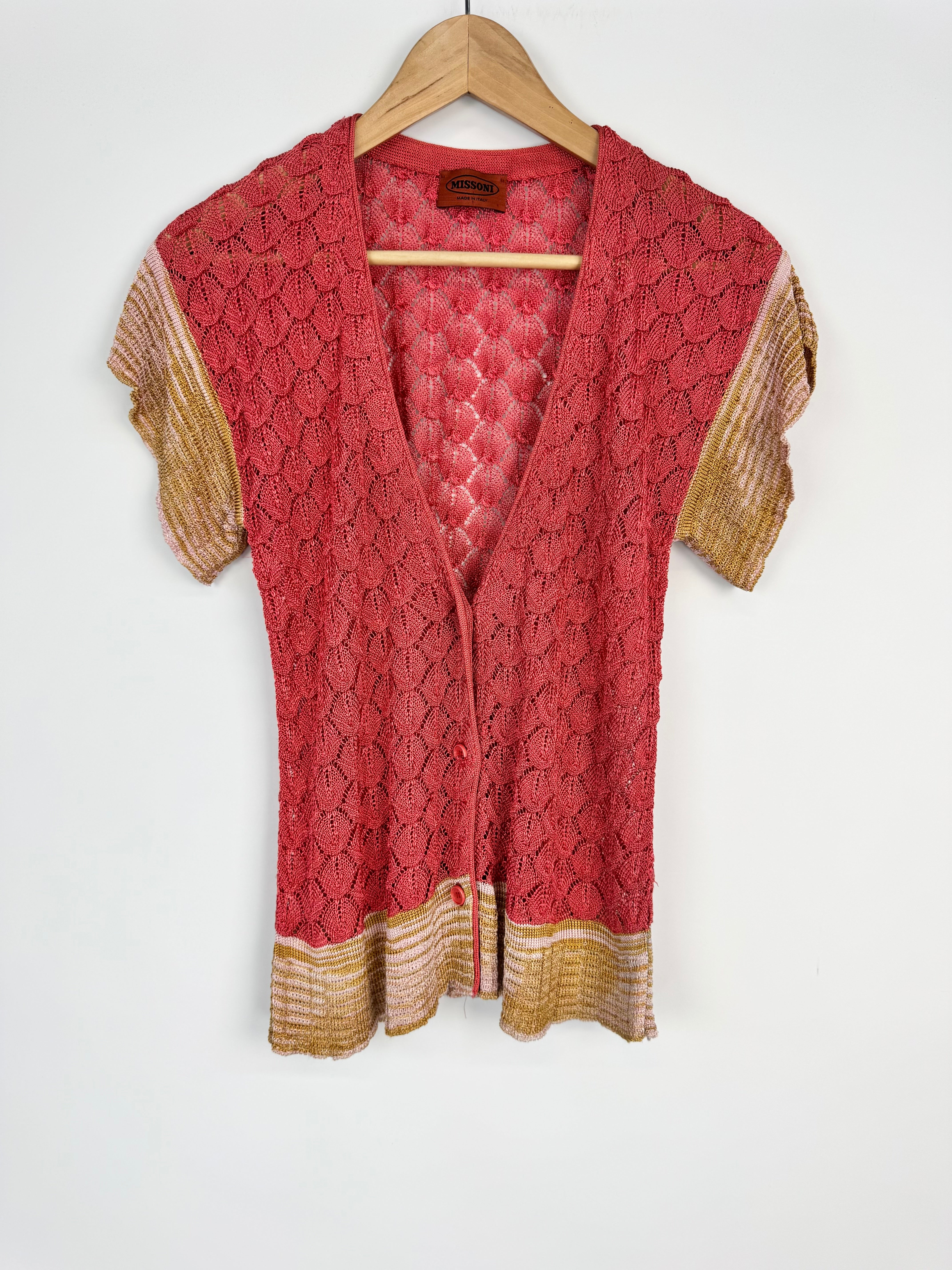 Red lace top with gold trim on a wooden hanger against a white background