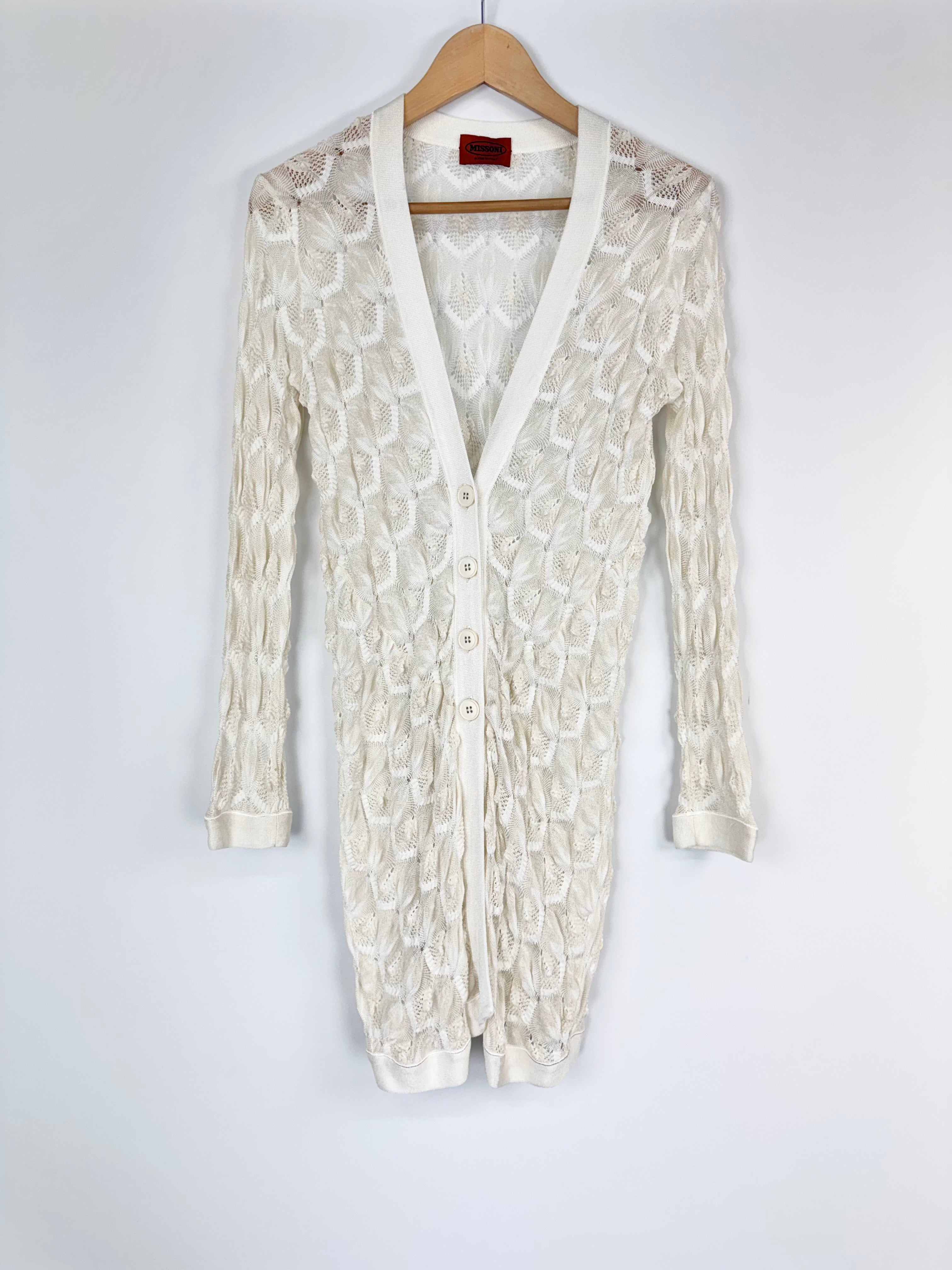 White lace cardigan on a hanger against a white background