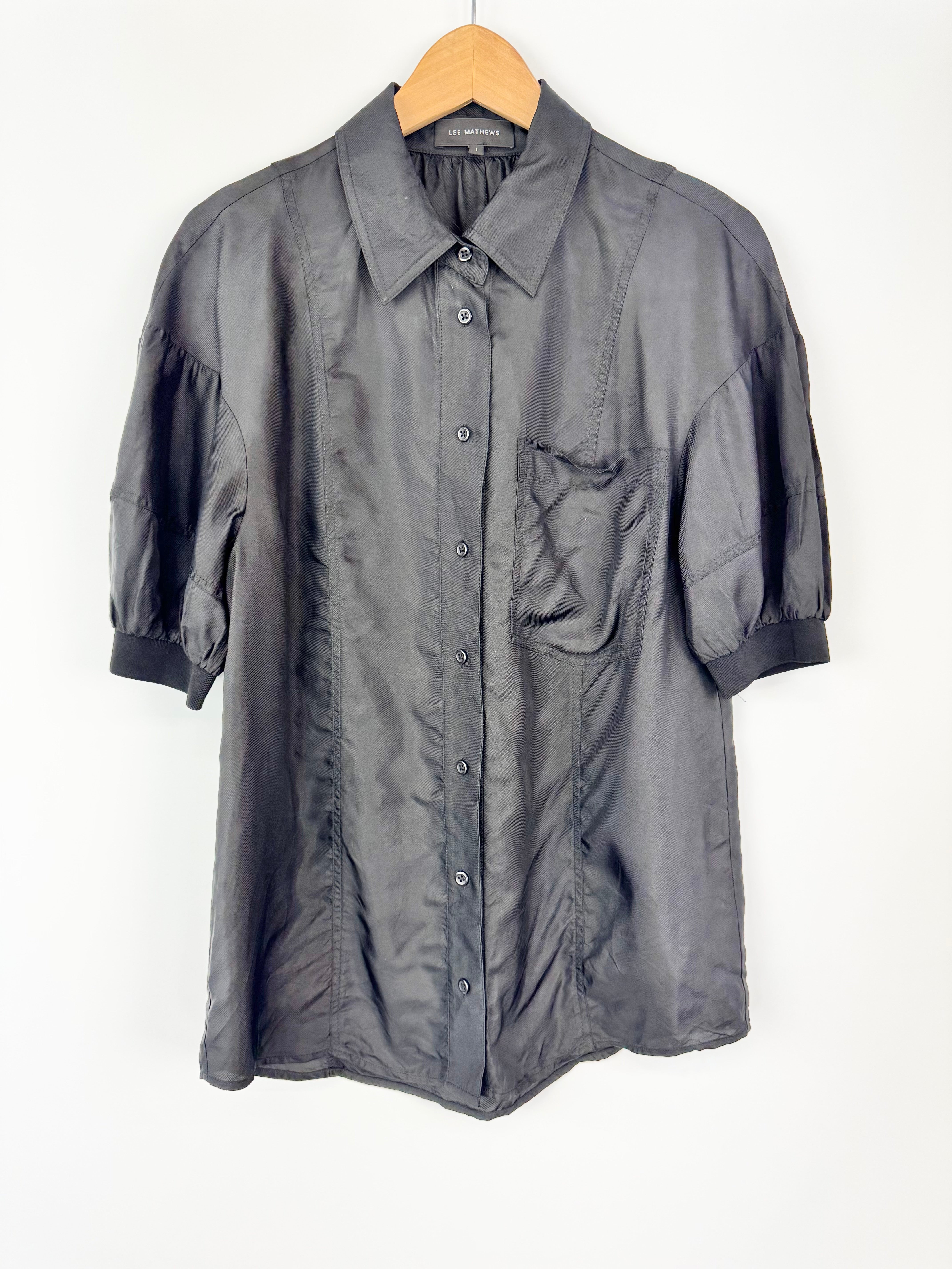 Black shirt with short sleeves on a hanger against a white background