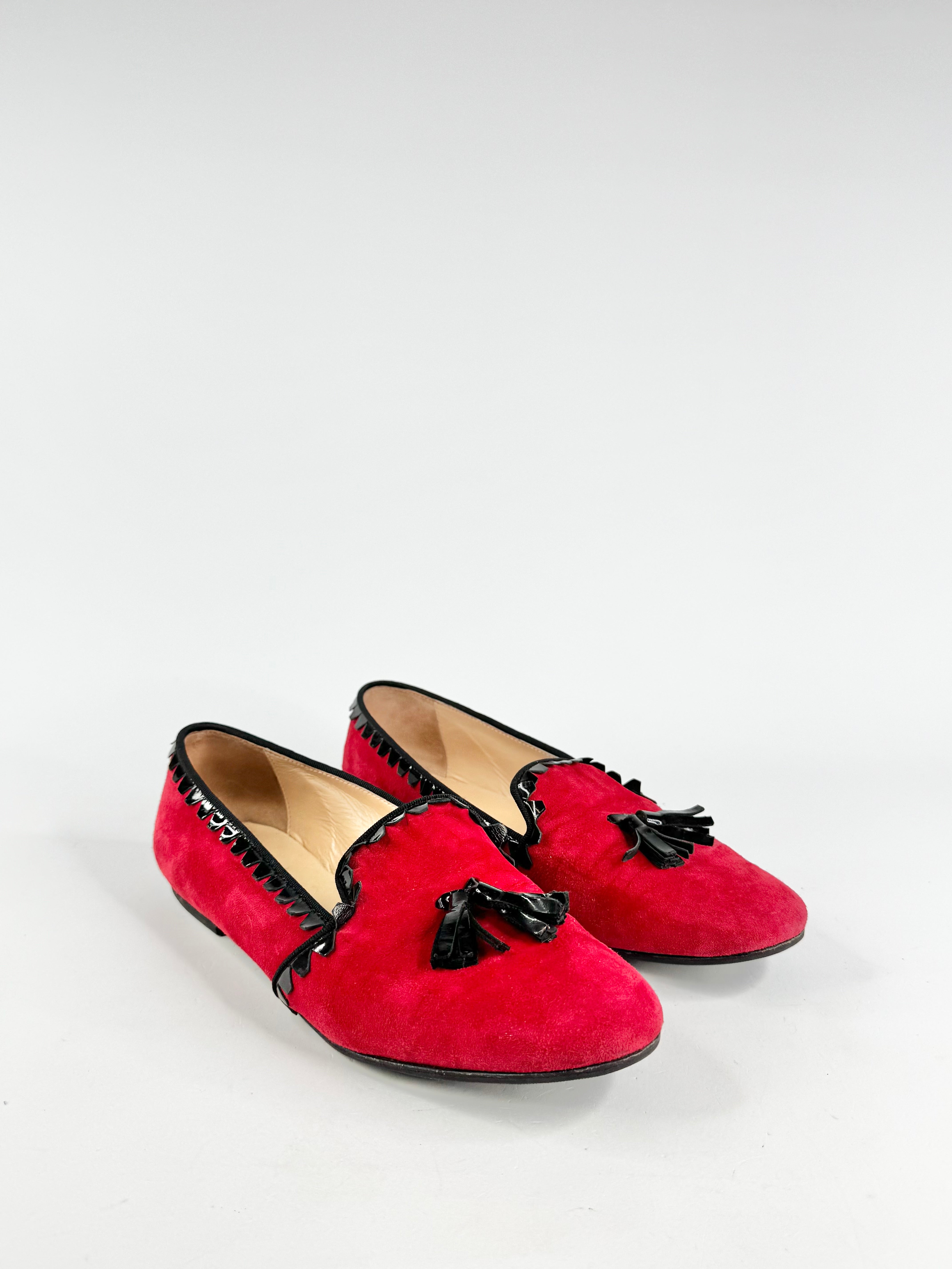 Red suede shoes with black tassels on a white background