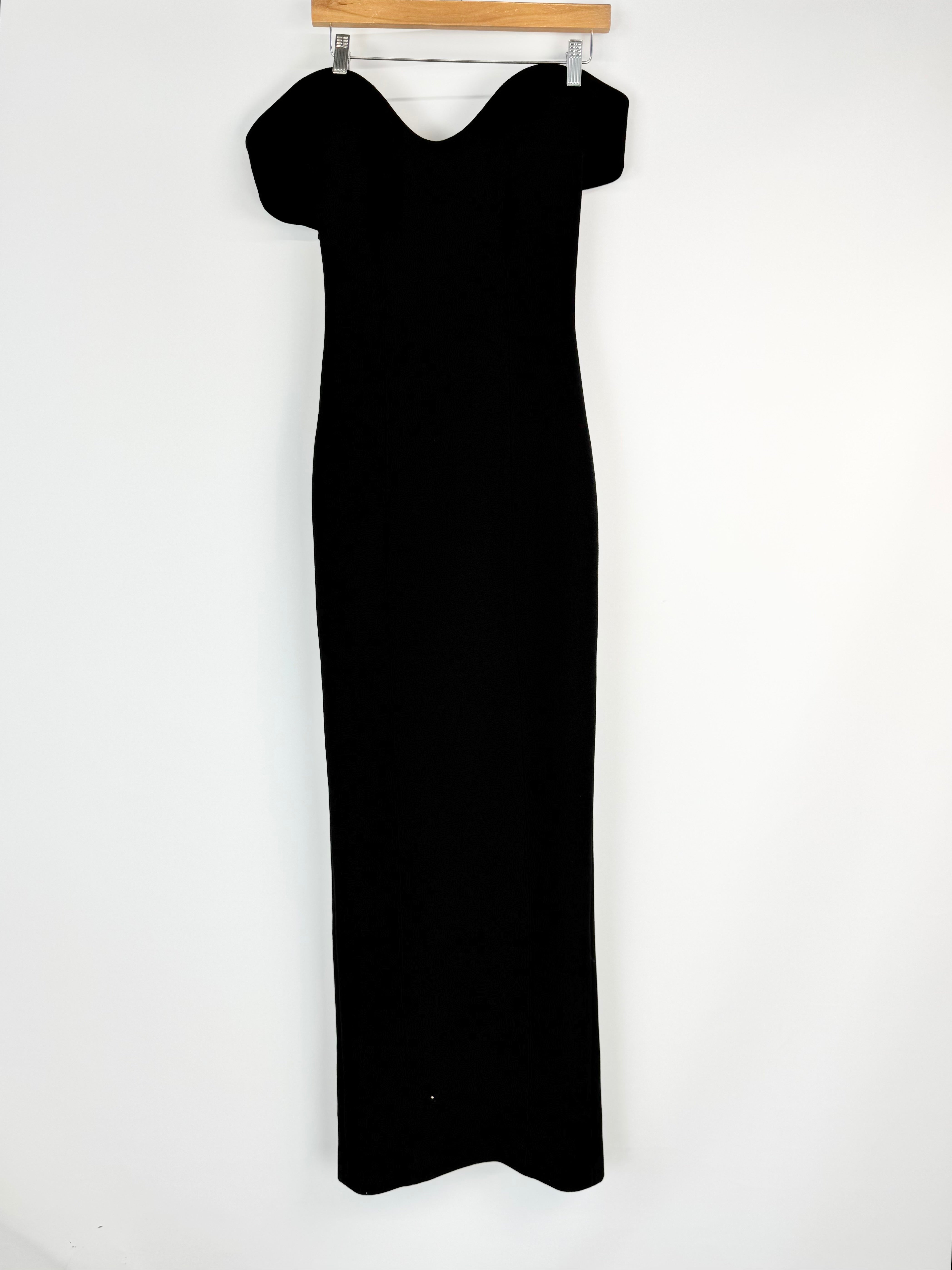 Black dress on a hanger against a white background