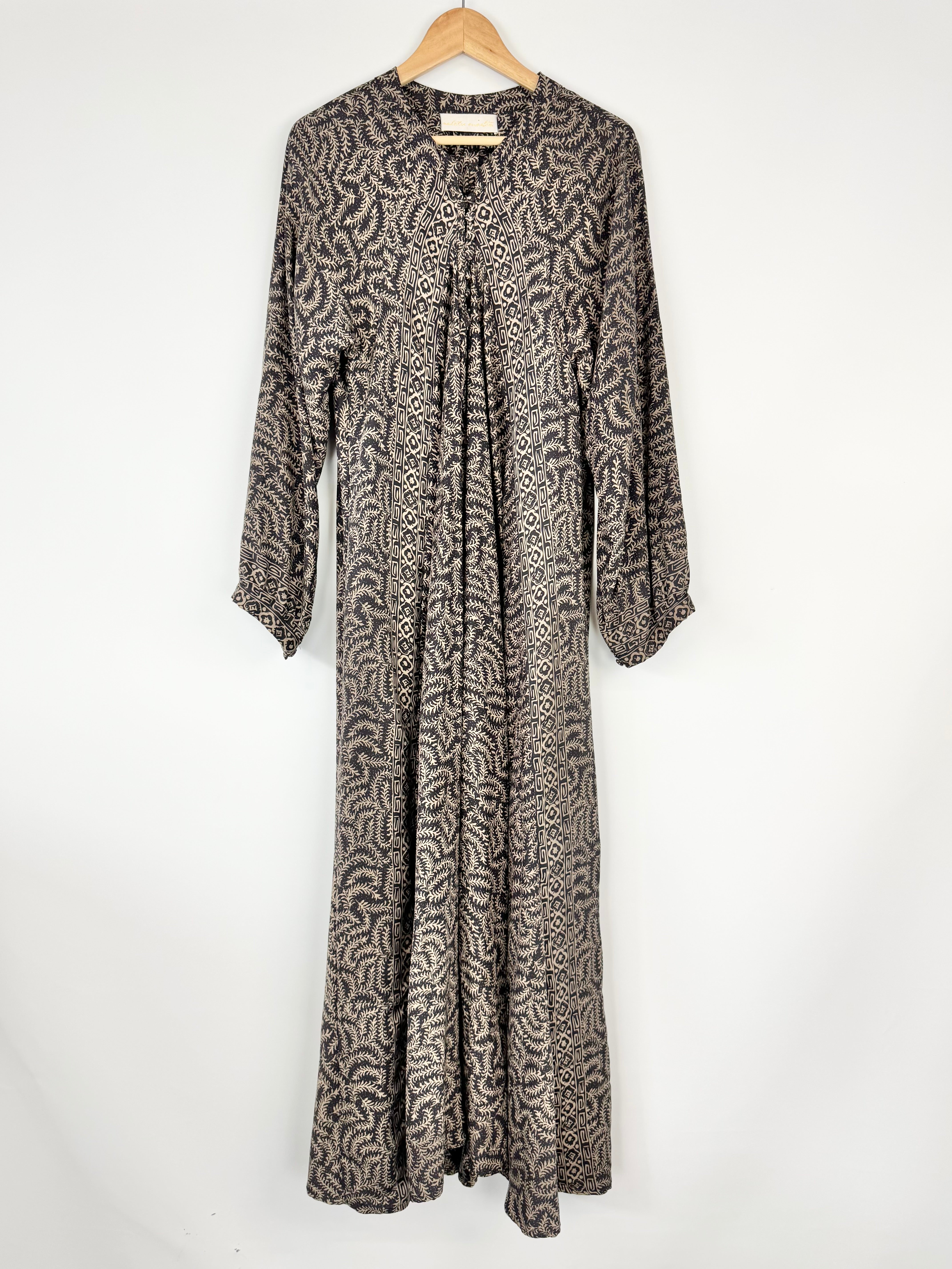Long patterned dress on a wooden hanger against a white background