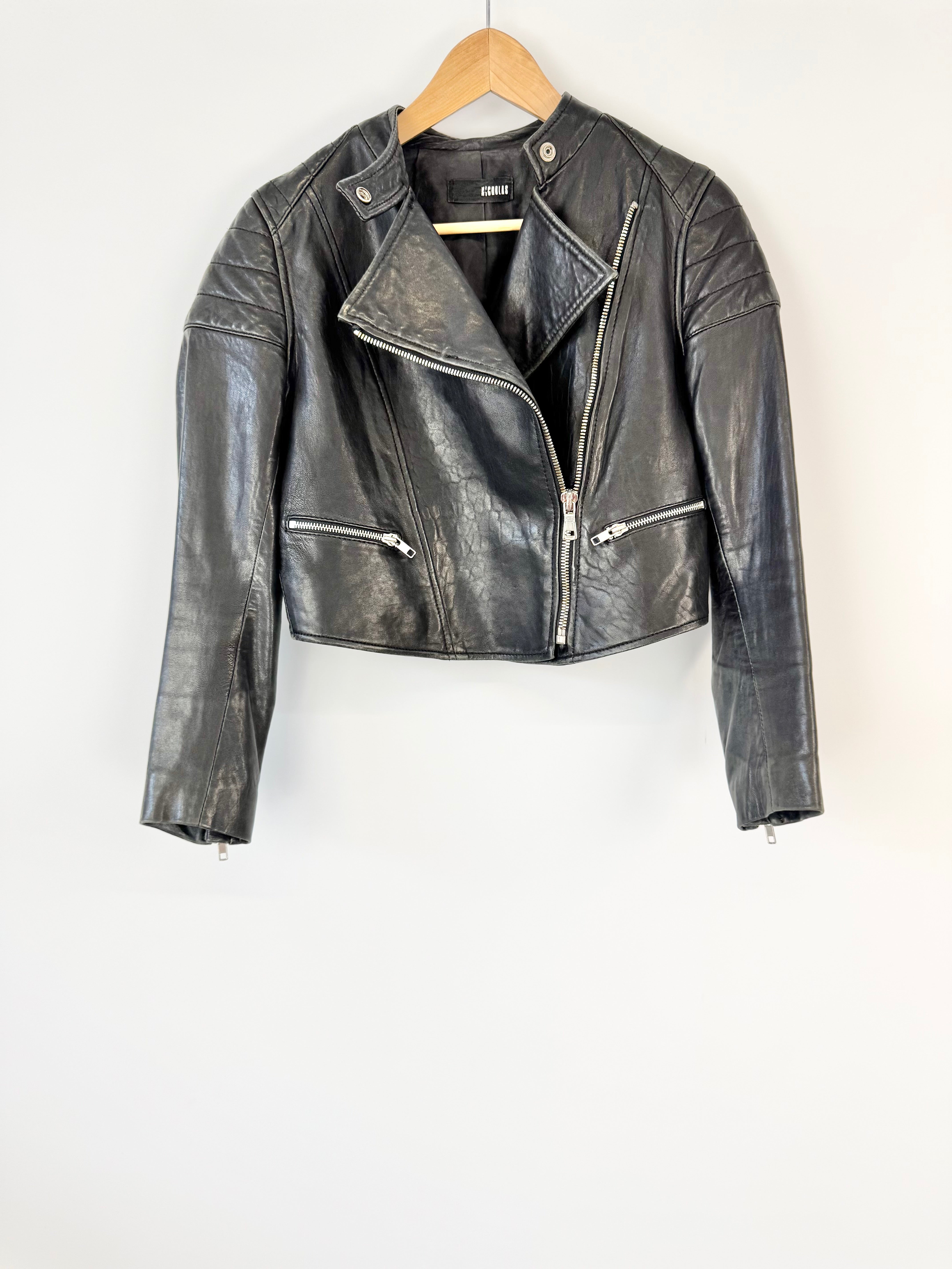 Black leather jacket on a hanger against a white background
