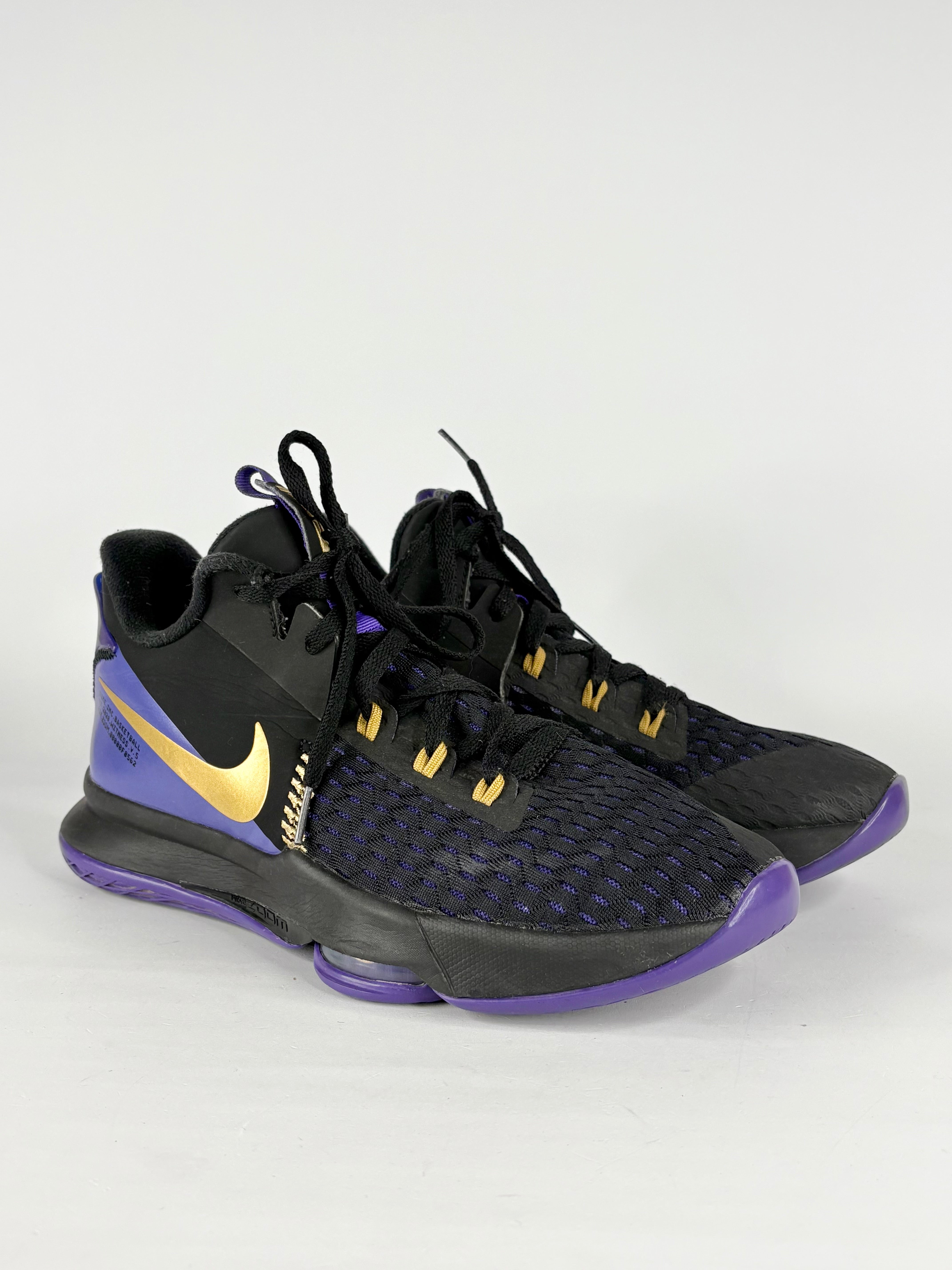 Pair of black and purple sneakers with gold accents on a white background