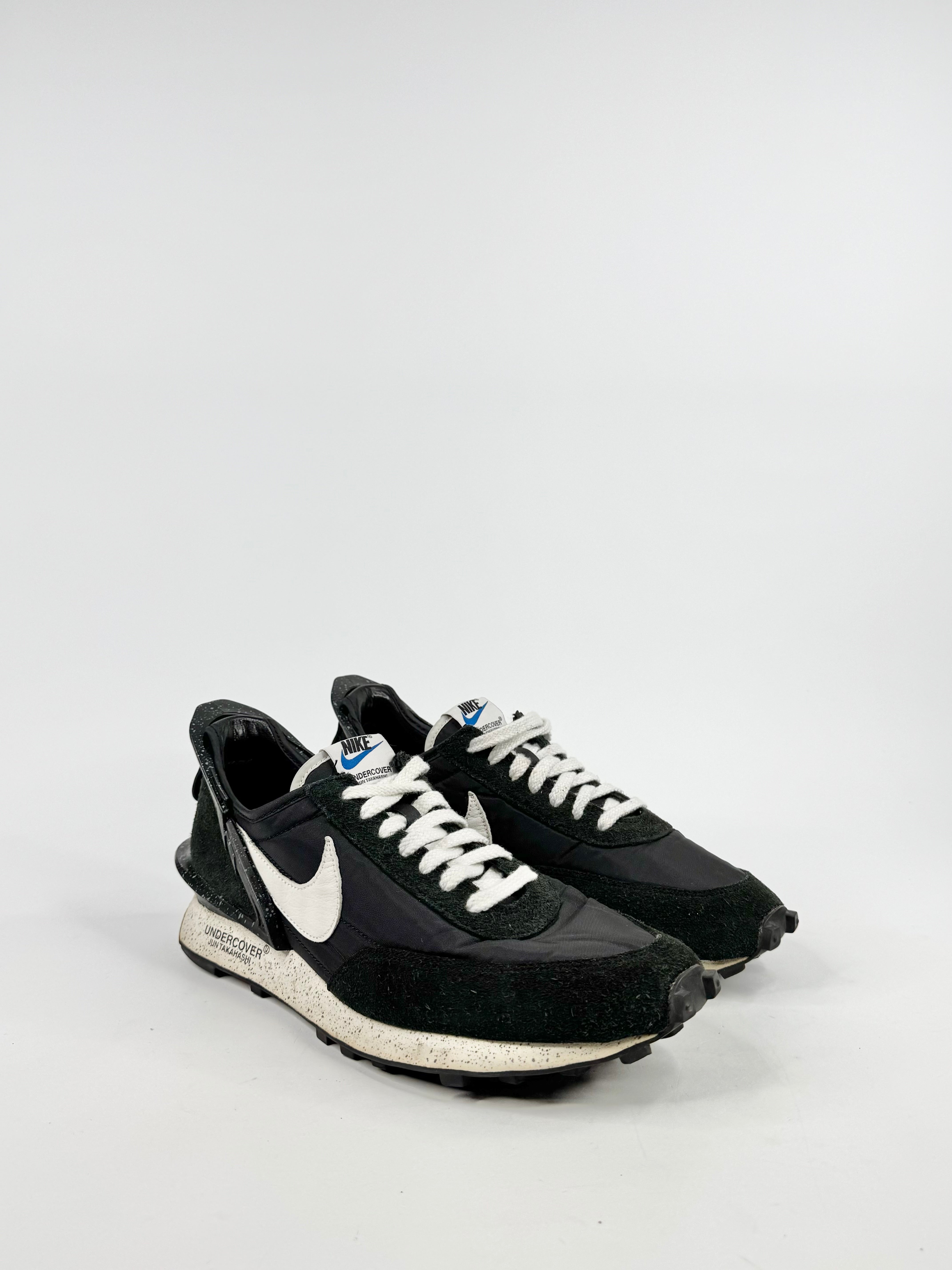 Black Nike sneakers with white accents on a light gray background