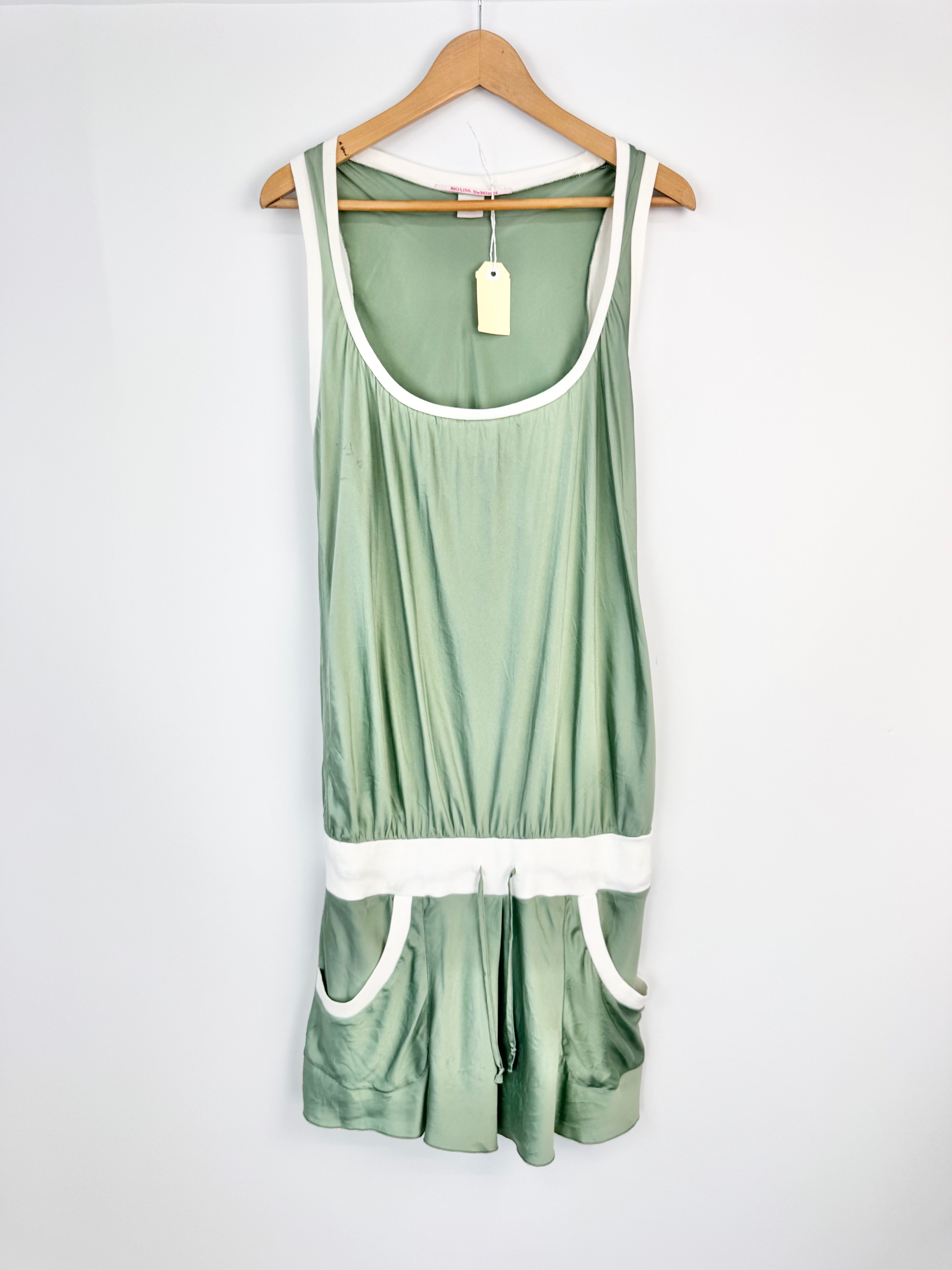 Green tank top and shorts set on a hanger against a white background