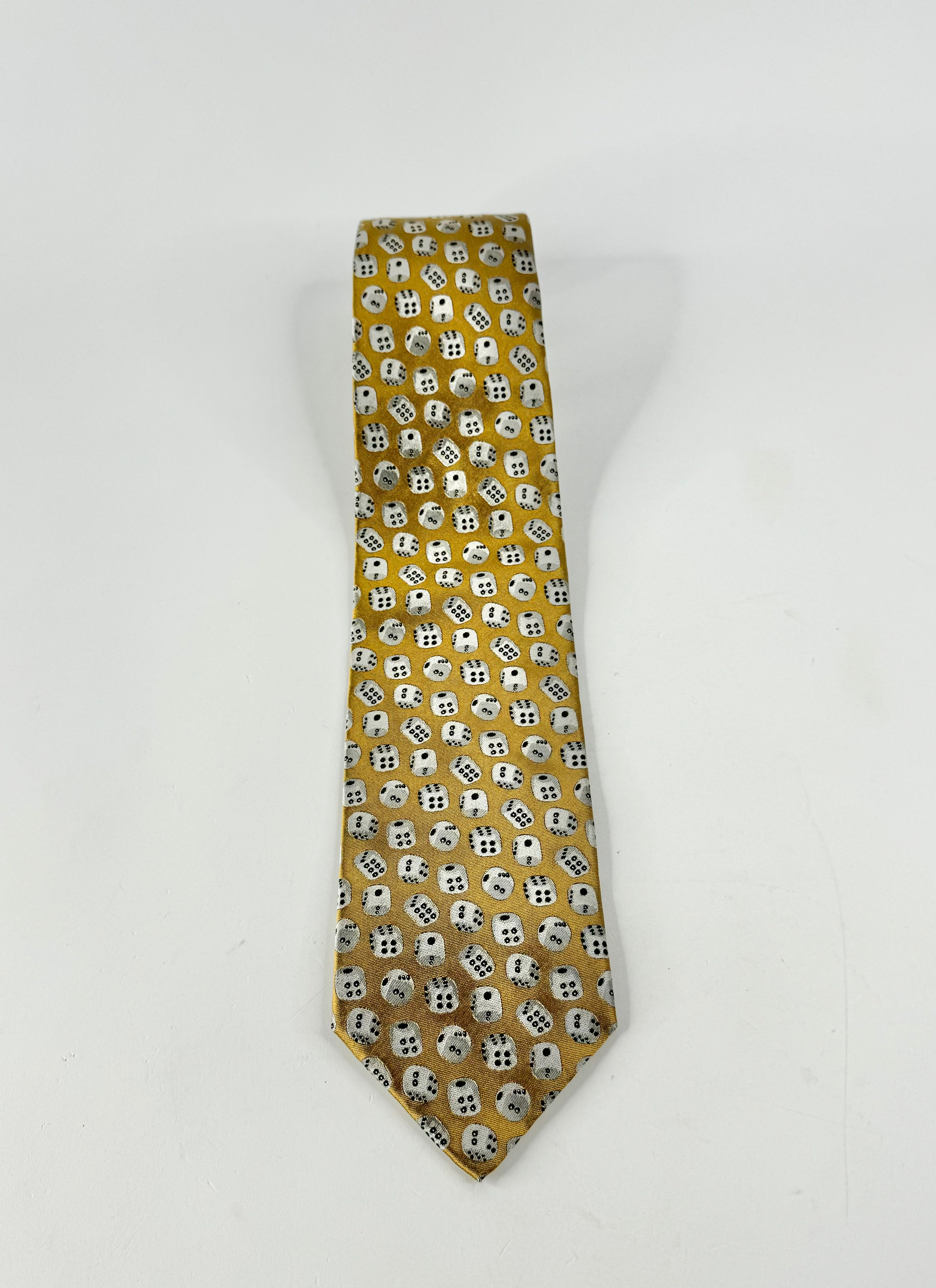 A gold necktie with a repeating pattern of white dice, photographed against a plain white background.