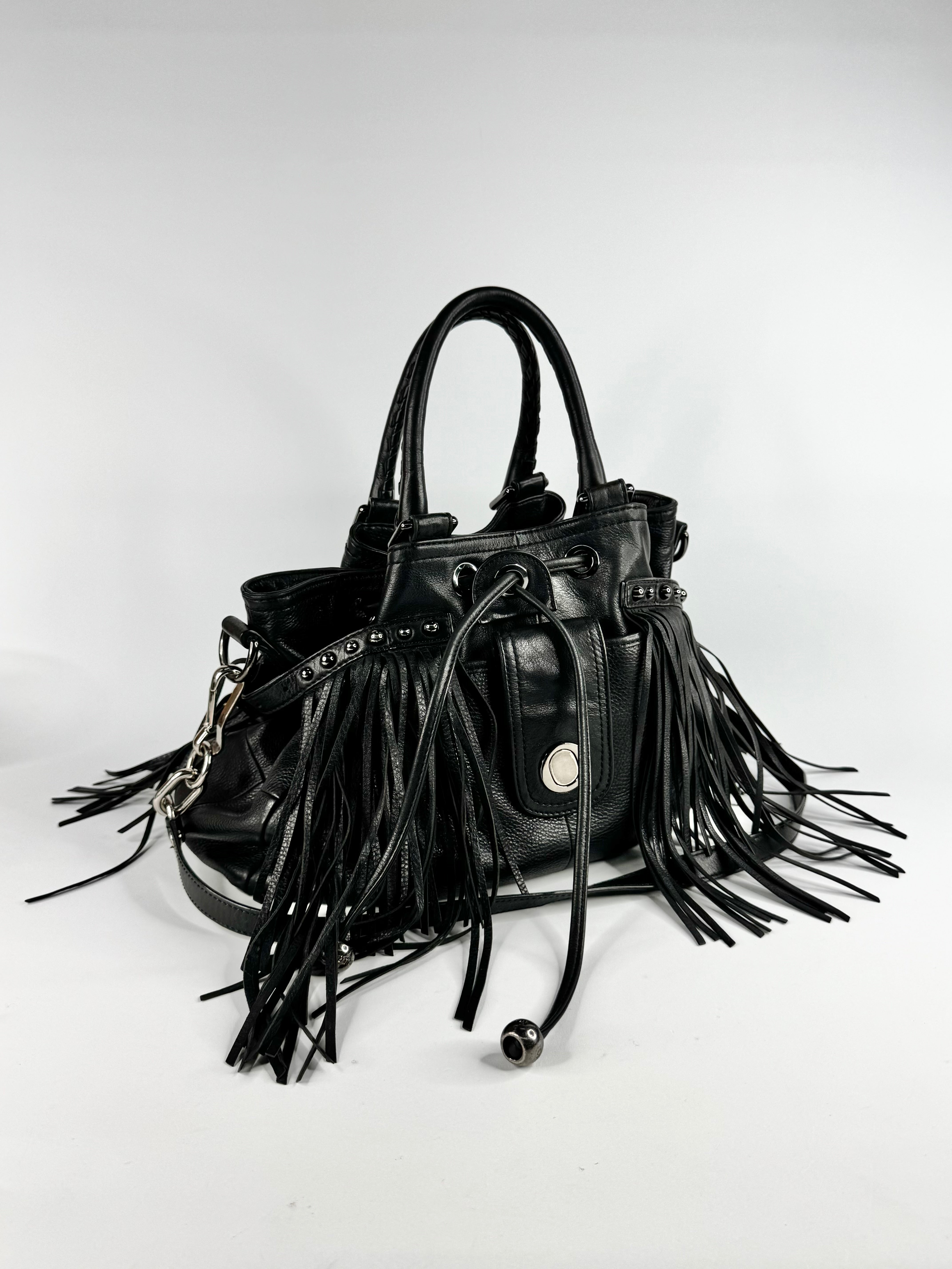 Black leather handbag with fringe details on a white background