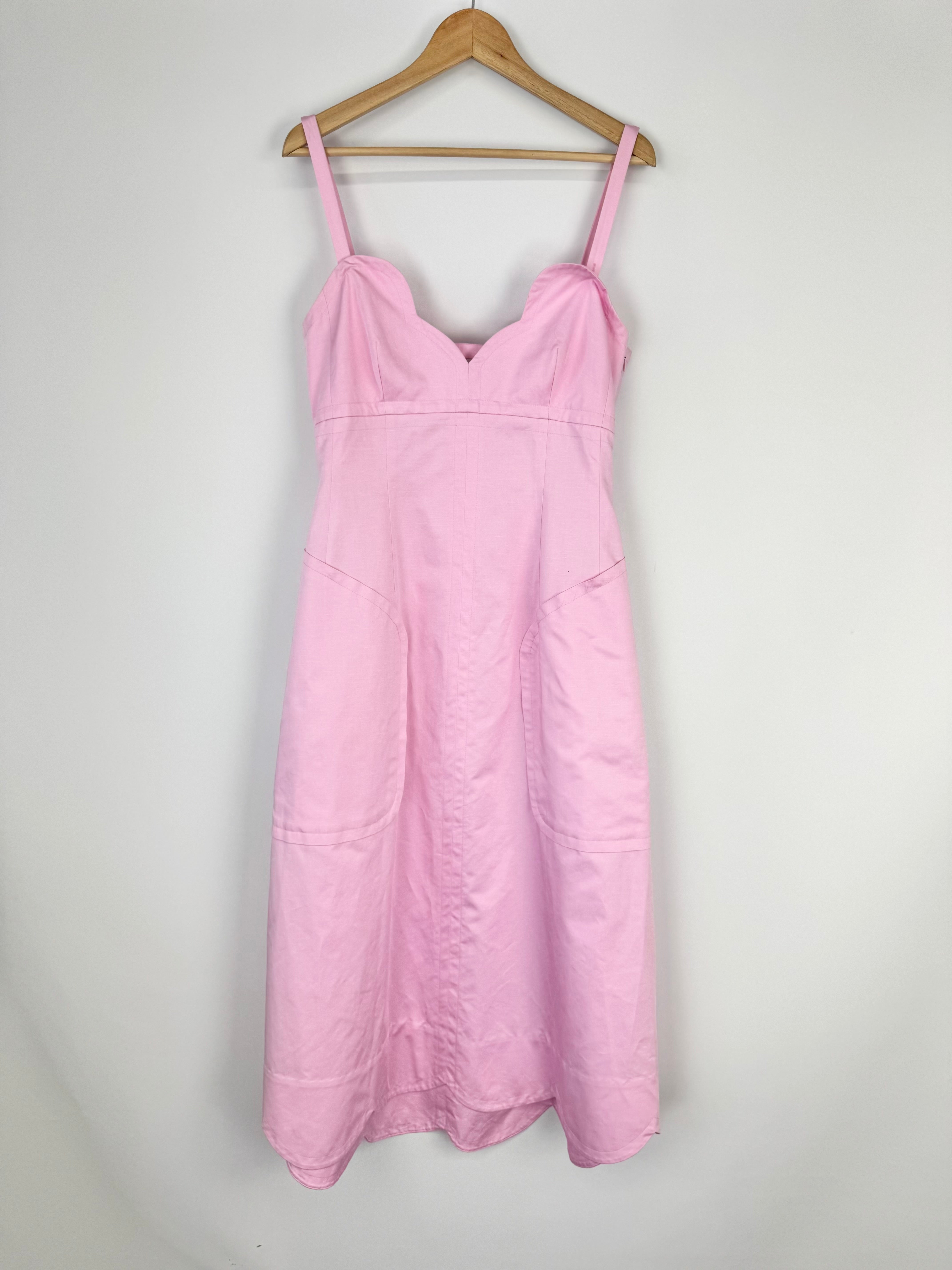 Pink dress on a wooden hanger against a white background