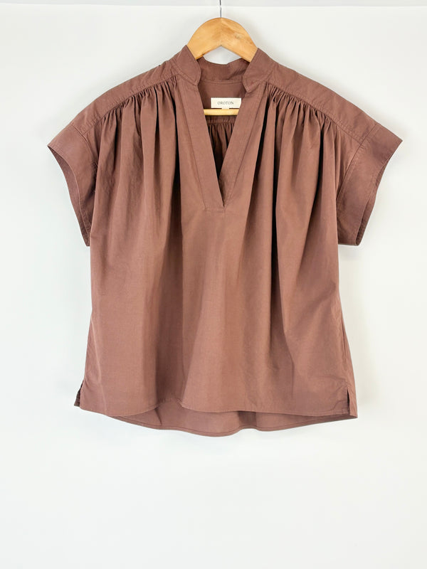Brown Oroton blouse on a wooden hanger against a white background