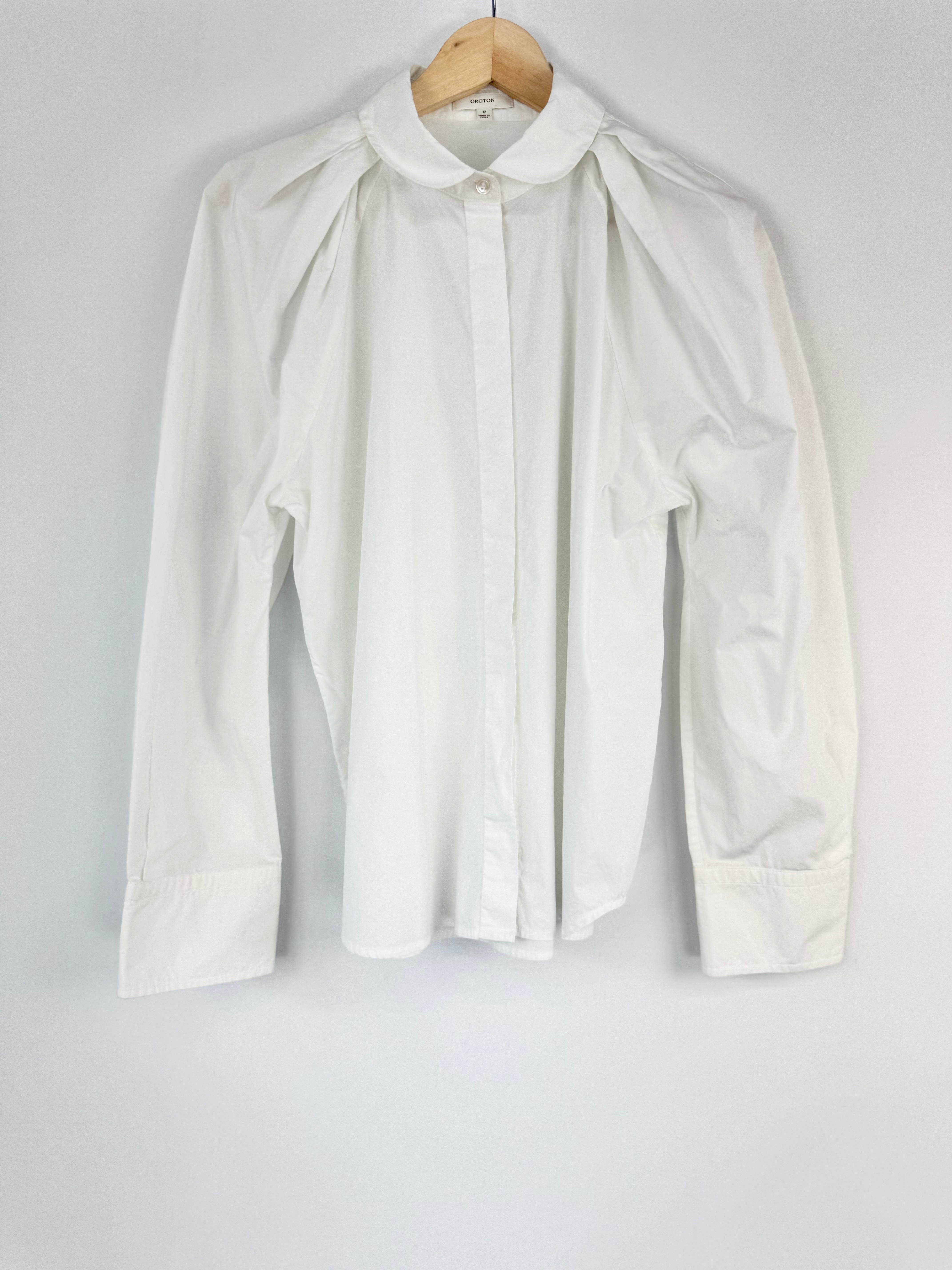 White blouse on a hanger against a plain background