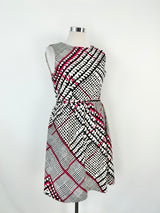 A silk midi dress with a geometric pattern in white, blue, and hot pink, featuring a rounded scoop neckline, zipper at the back, and a fine, small belted tie at the waist.