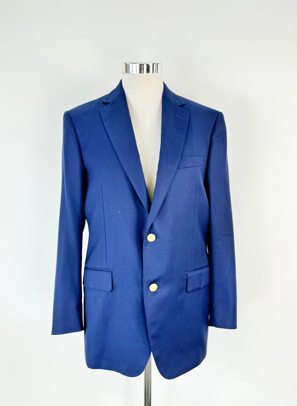 A deep cobalt blue blazer with gold toned buttons and a navy silky lining, displayed on a mannequin against a white background.