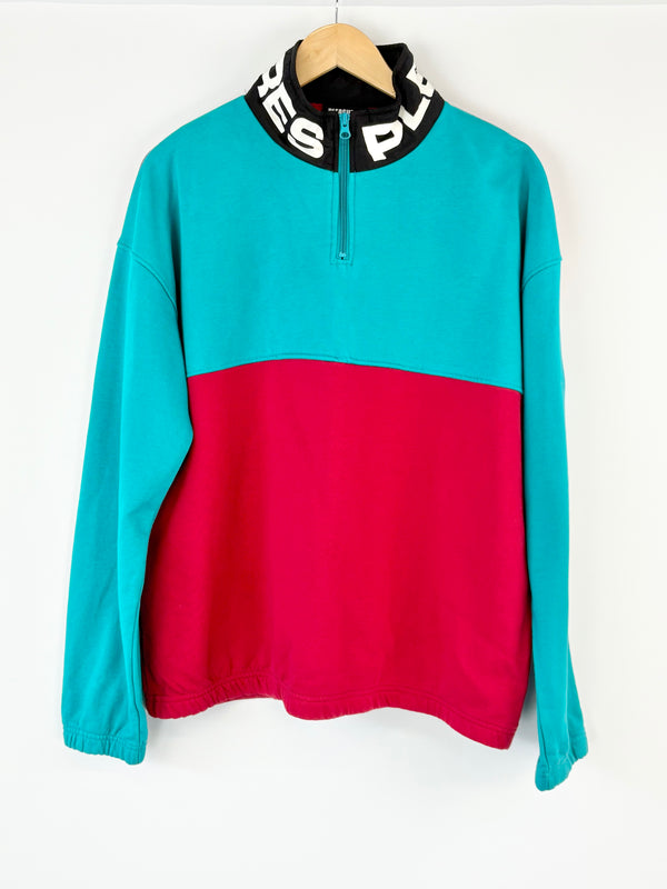 Color-blocked pullover with turquoise top and red bottom on a white background