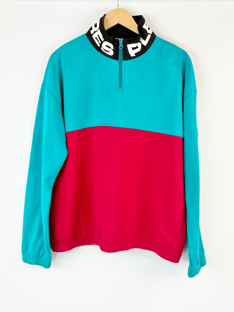 Color-blocked pullover with turquoise top and red bottom on a white background