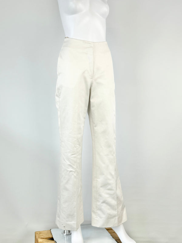 A pair of white cotton slacks displayed on a mannequin against a white background.