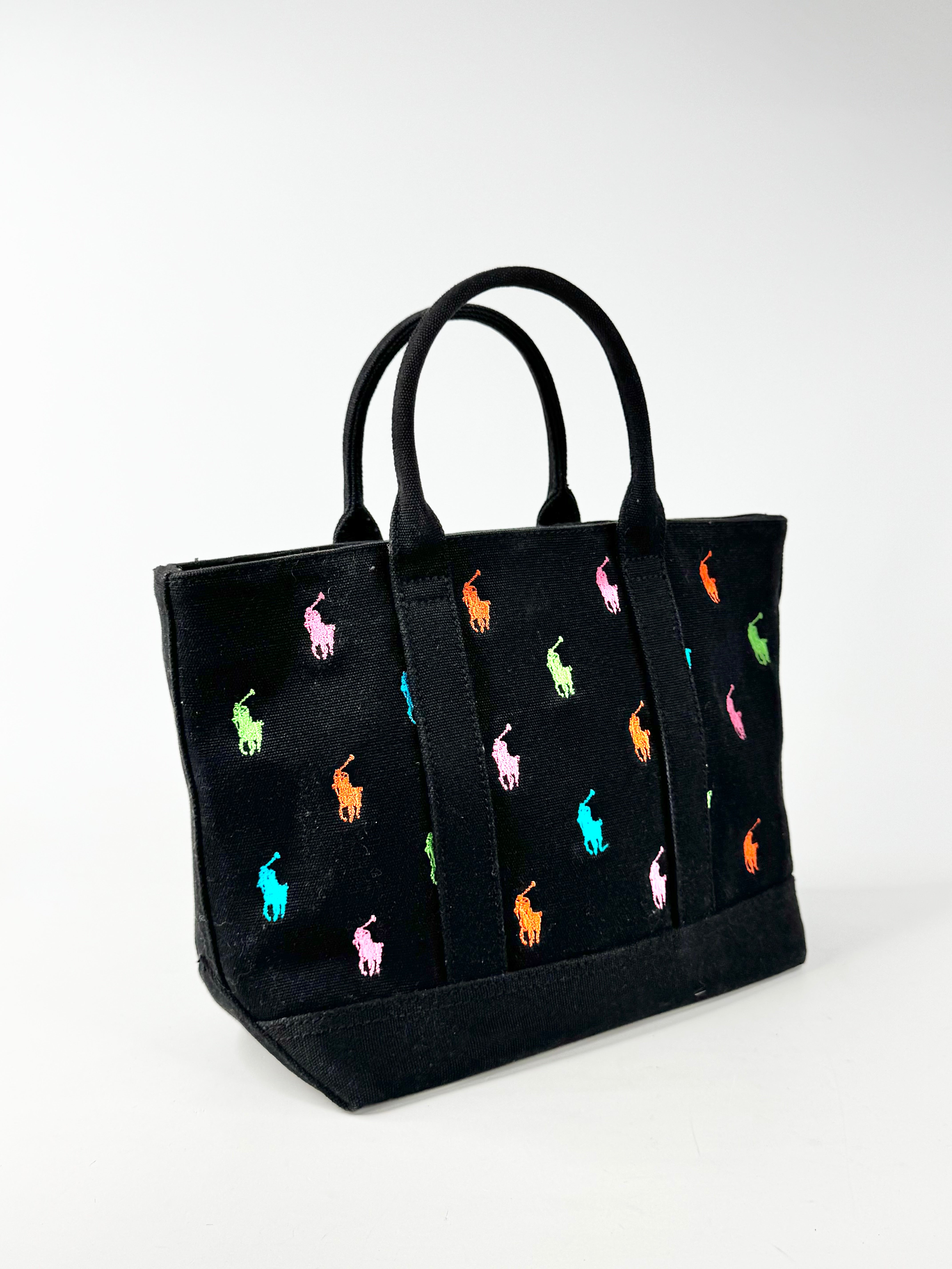 Black tote bag with colorful embroidered designs on a white background