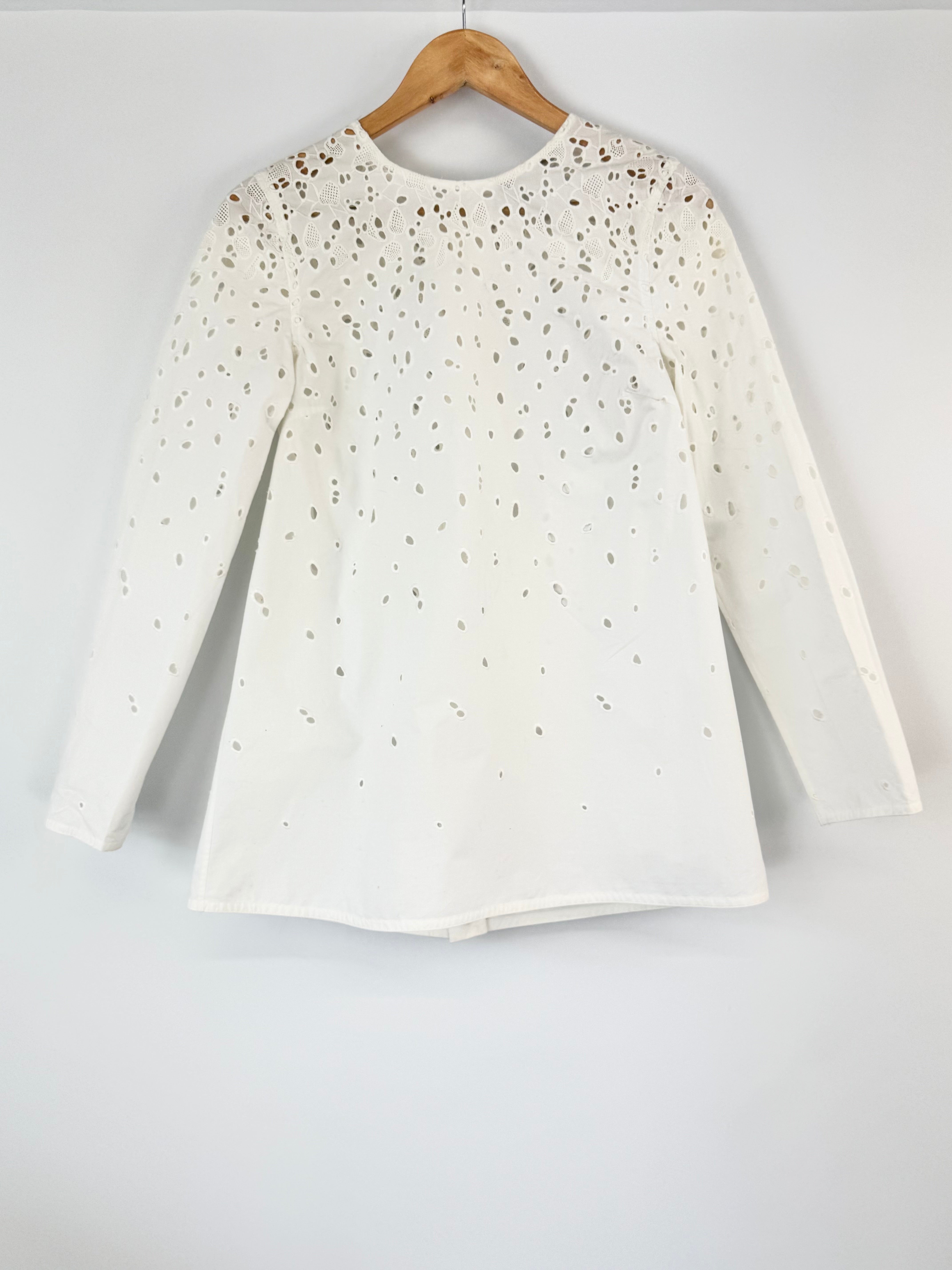 White long-sleeve shirt with subtle pattern on a wooden hanger against a white background