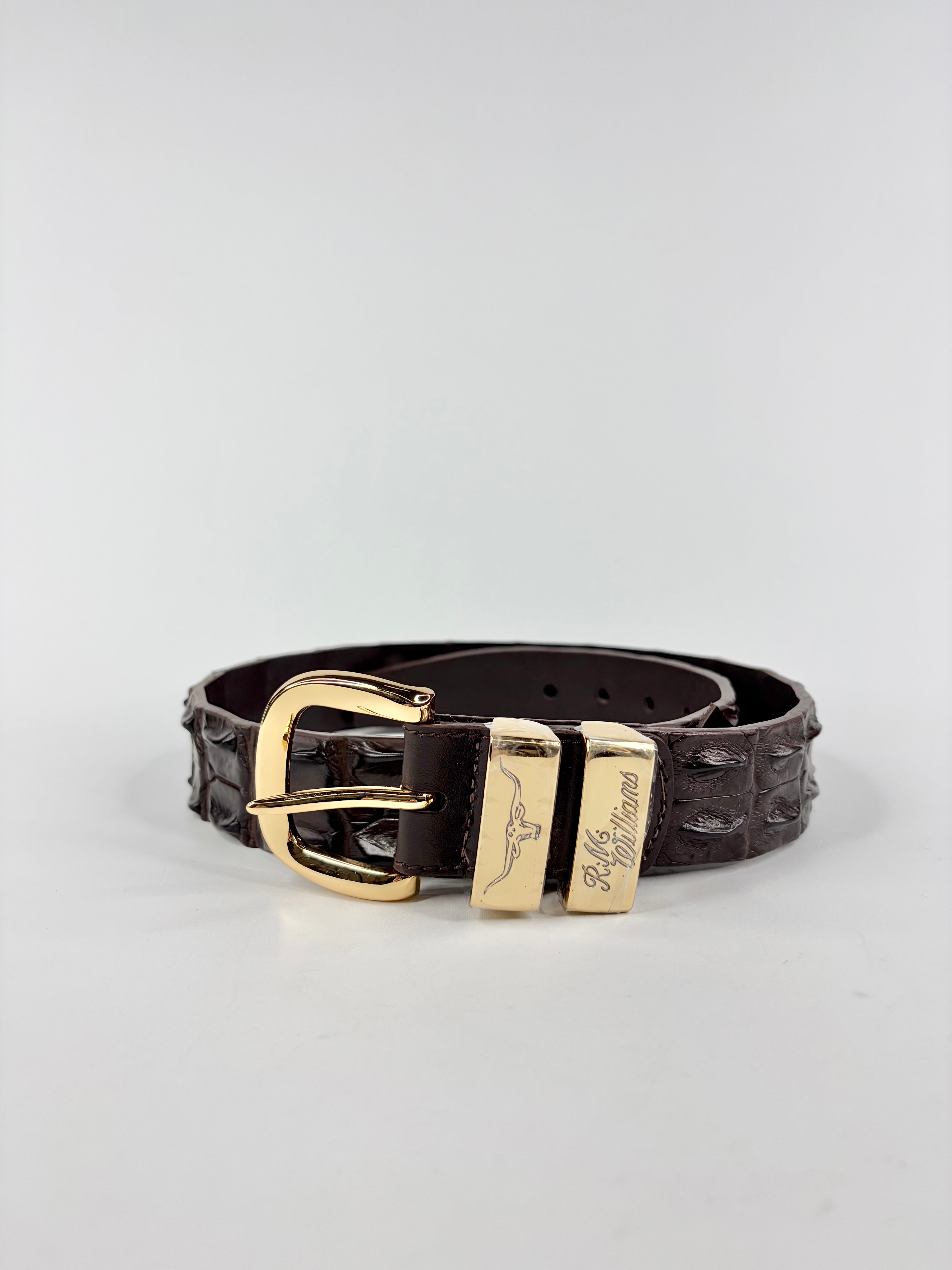 Brown leather belt with gold buckle on a light gray background