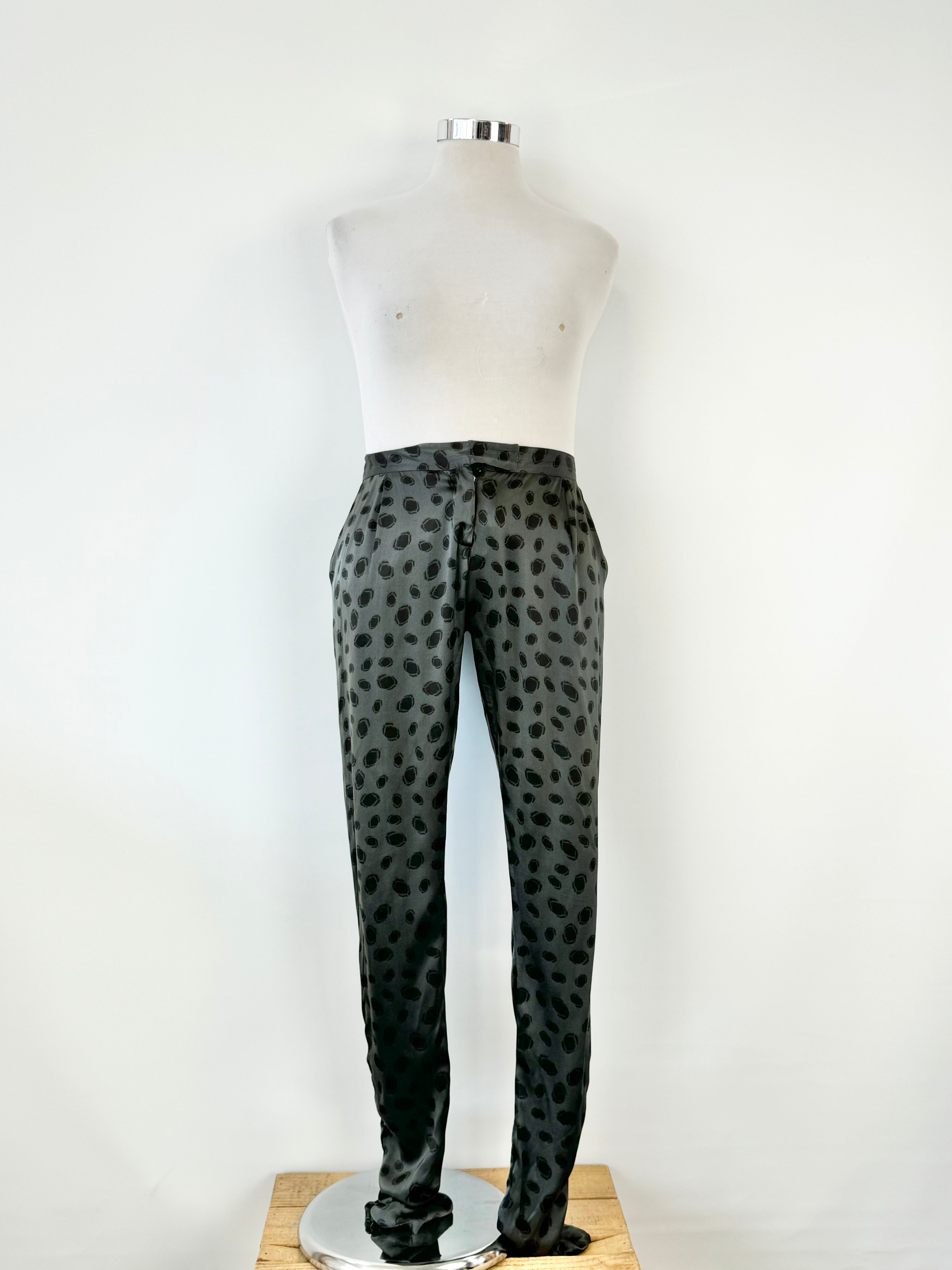 A pair of black silk dotted slacks displayed on a mannequin against a white background.