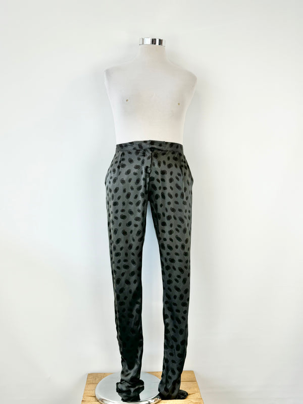 A pair of black silk dotted slacks displayed on a mannequin against a white background.
