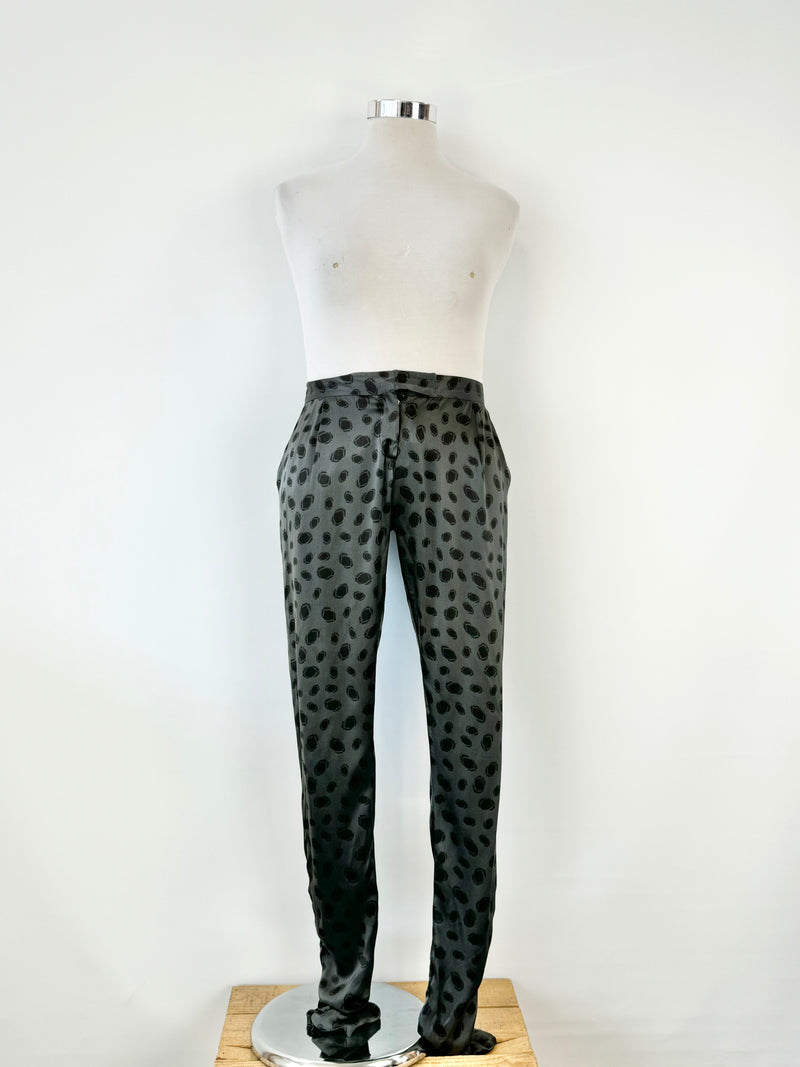 A pair of black silk dotted slacks displayed on a mannequin against a white background.