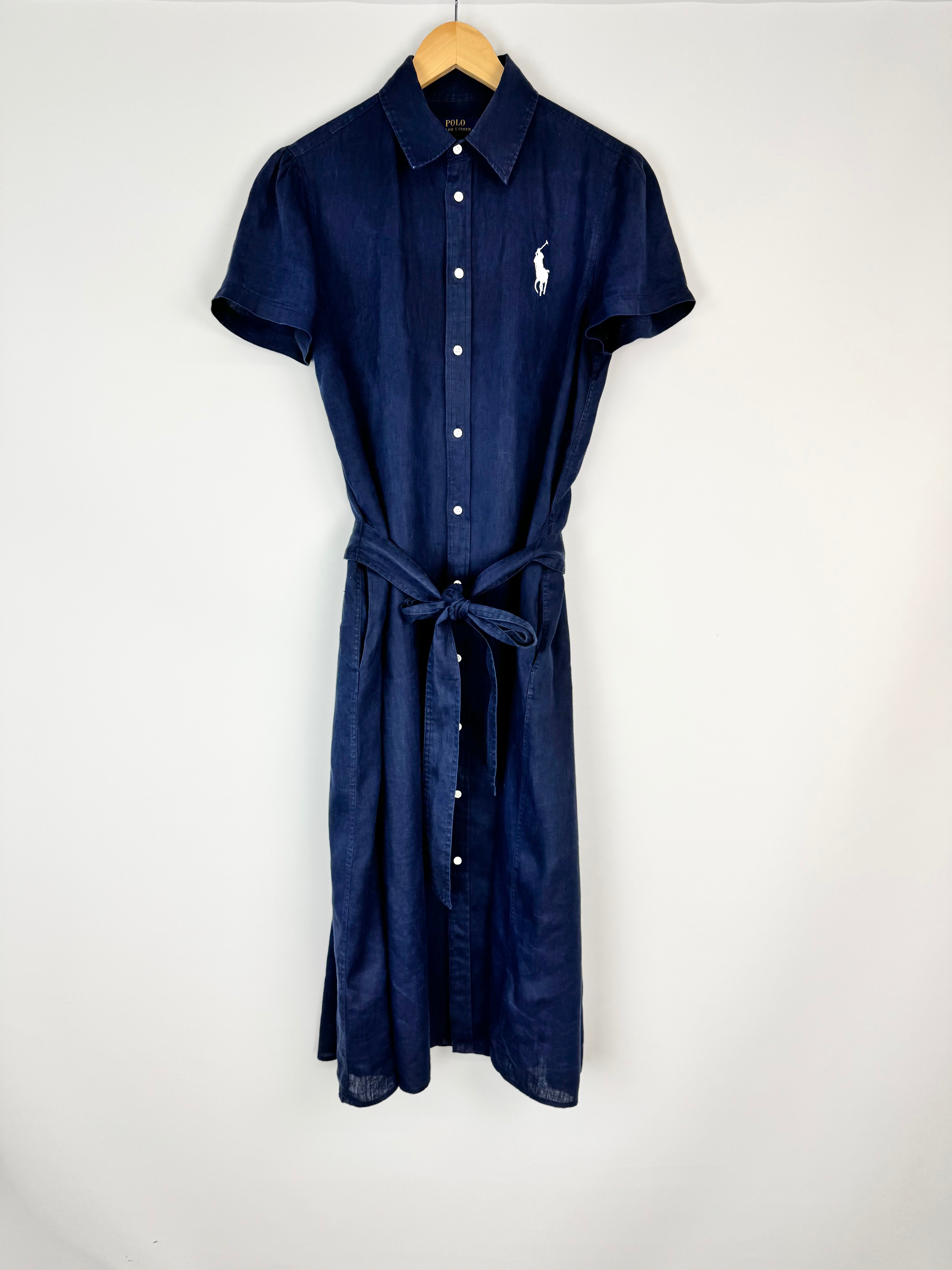 Navy blue dress with a belt on a hanger against a white background