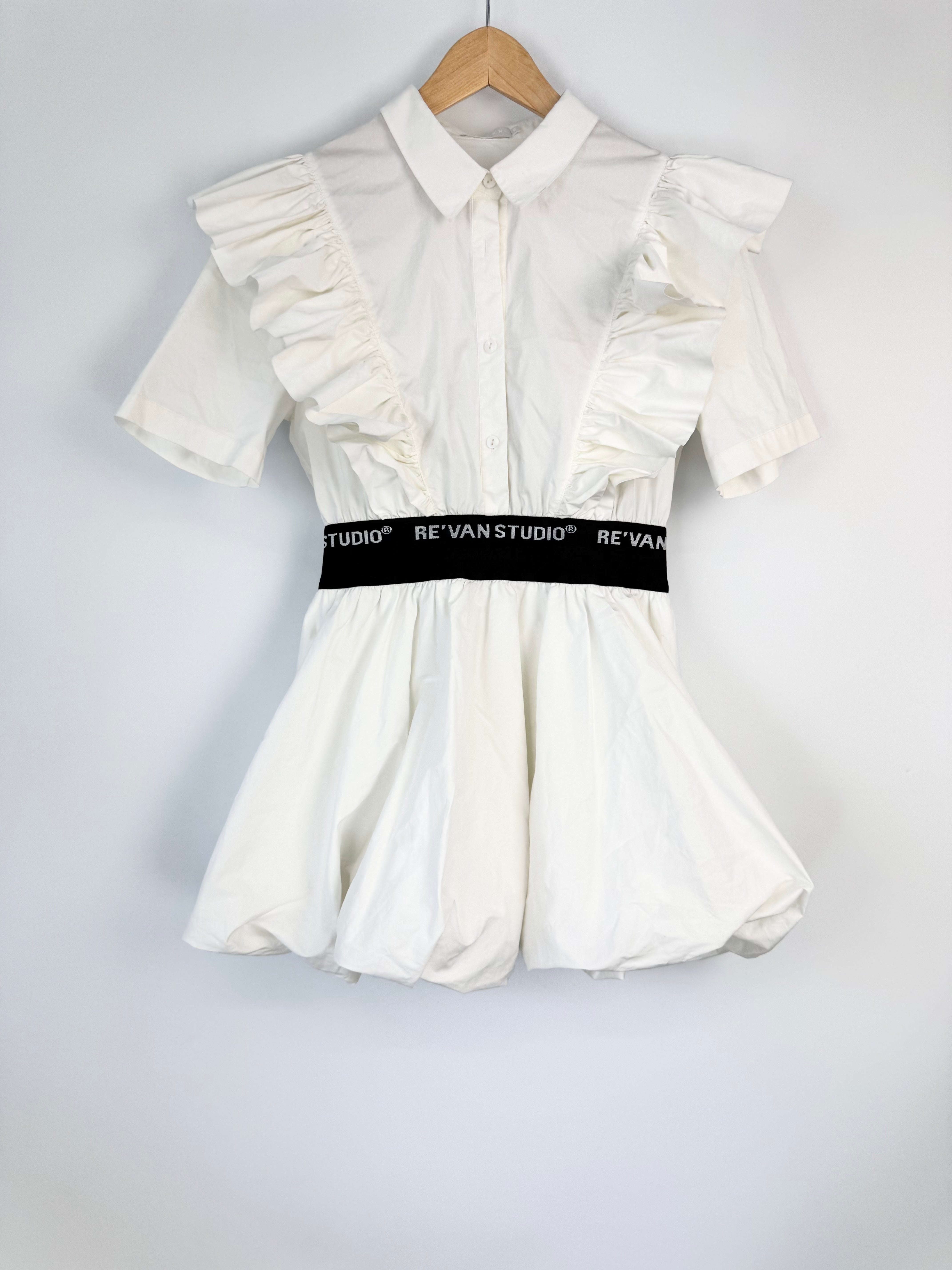 White dress with ruffled sleeves on a hanger against a light gray background