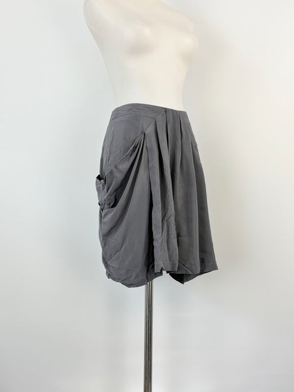 A grey satin mini skirt displayed on a mannequin, showing a side slit and a high waist.